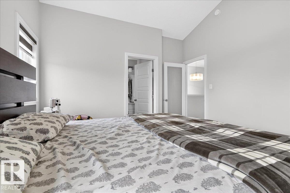 This bedroom features light gray walls, a window with blinds, and a dark-colored bed frame - 203 Cavanagh Common, Edmonton, AB - Indoor Photo Showing Bedroom