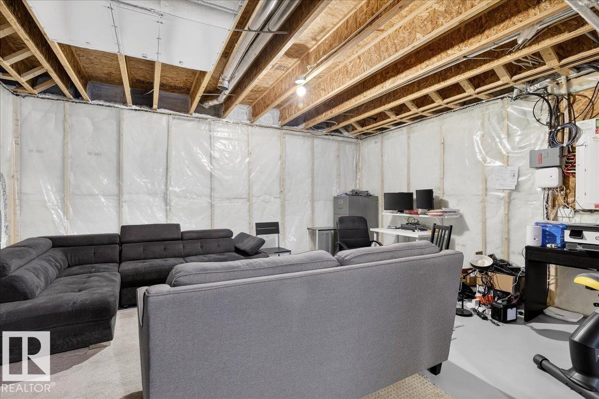 The property features an unfinished basement with exposed ceiling joists and visible insulation, offering potential for customization - 203 Cavanagh Common, Edmonton, AB - Indoor Photo Showing Basement