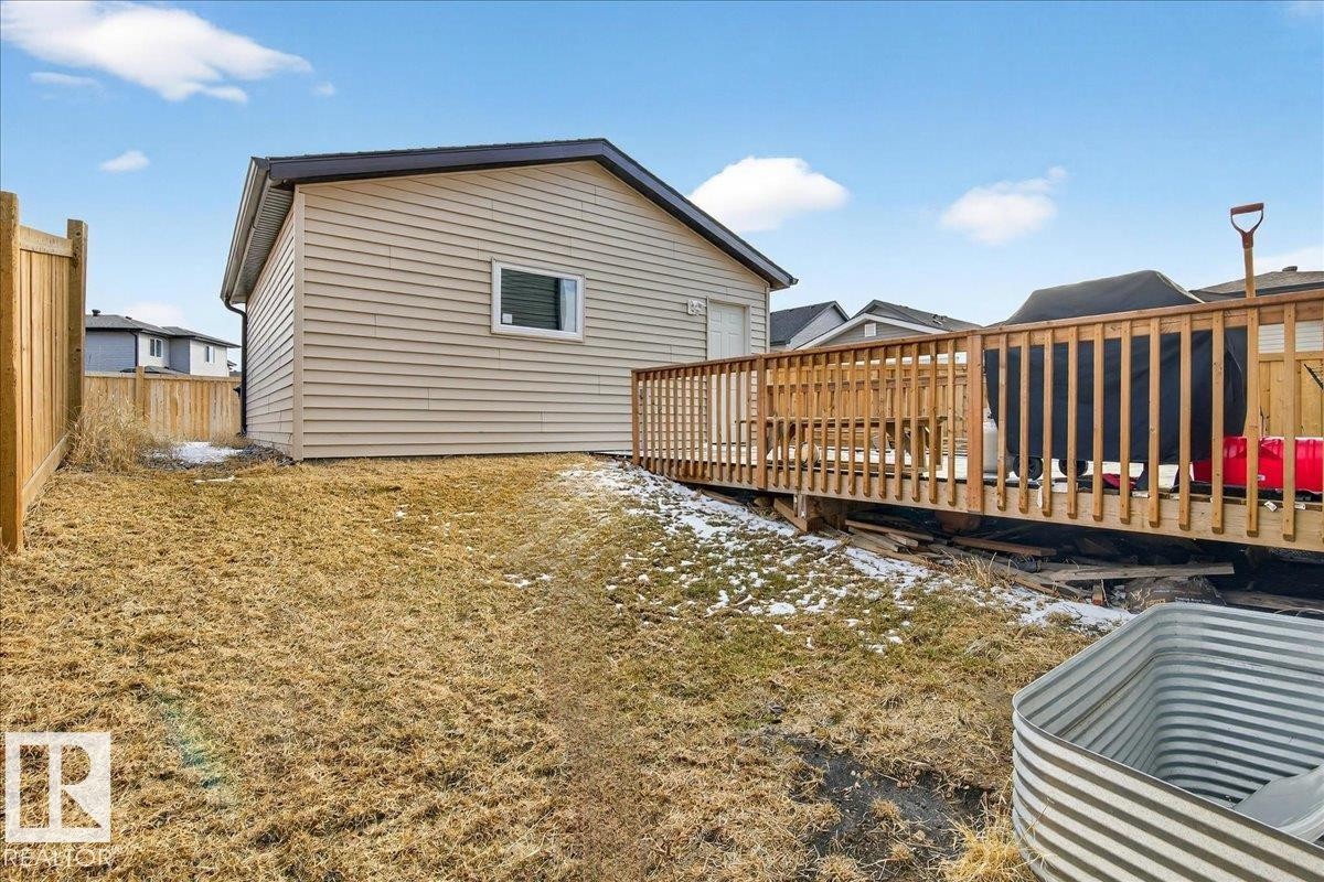 The property features a fenced yard with a wooden deck - 203 Cavanagh Common, Edmonton, AB - Outdoor With Deck Patio Veranda With Exterior