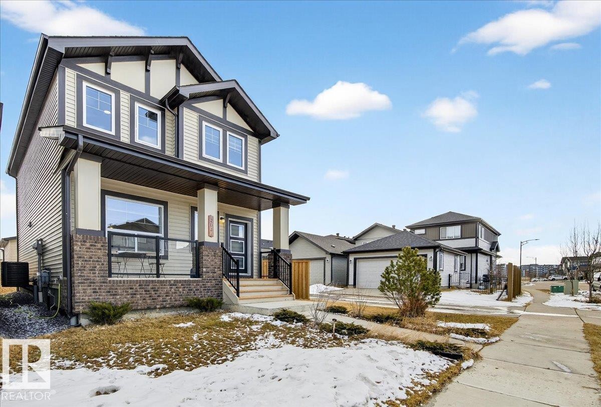 The property features a two-story elevation with a pitched roof and a covered porch - 203 Cavanagh Common, Edmonton, AB - Outdoor With Deck Patio Veranda