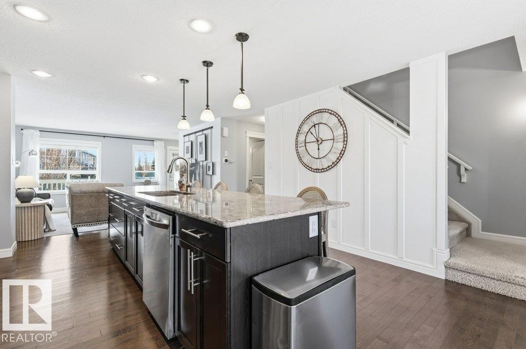 The property features a kitchen island with a granite countertop, an integrated sink with a gooseneck faucet, and stainless steel appliances - 16720 15 Avenue, Edmonton, AB - Indoor Photo Showing Kitchen With Upgraded Kitchen