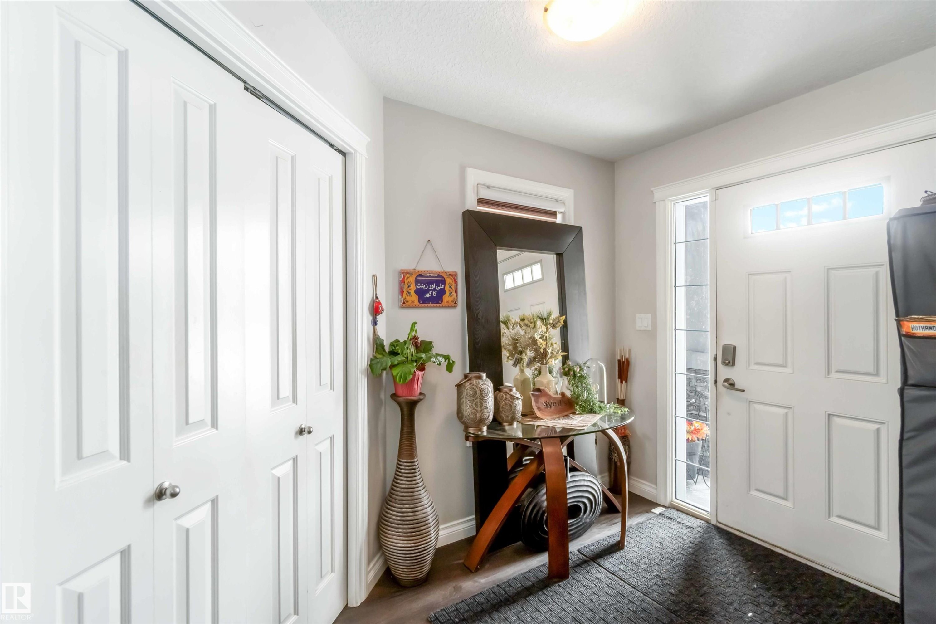 Entryway featuring a white paneled door with a sidelight and transom window, a closet with bifold doors, and dark flooring - 12232 167B Avenue, Edmonton, AB - Indoor Photo Showing Other Room