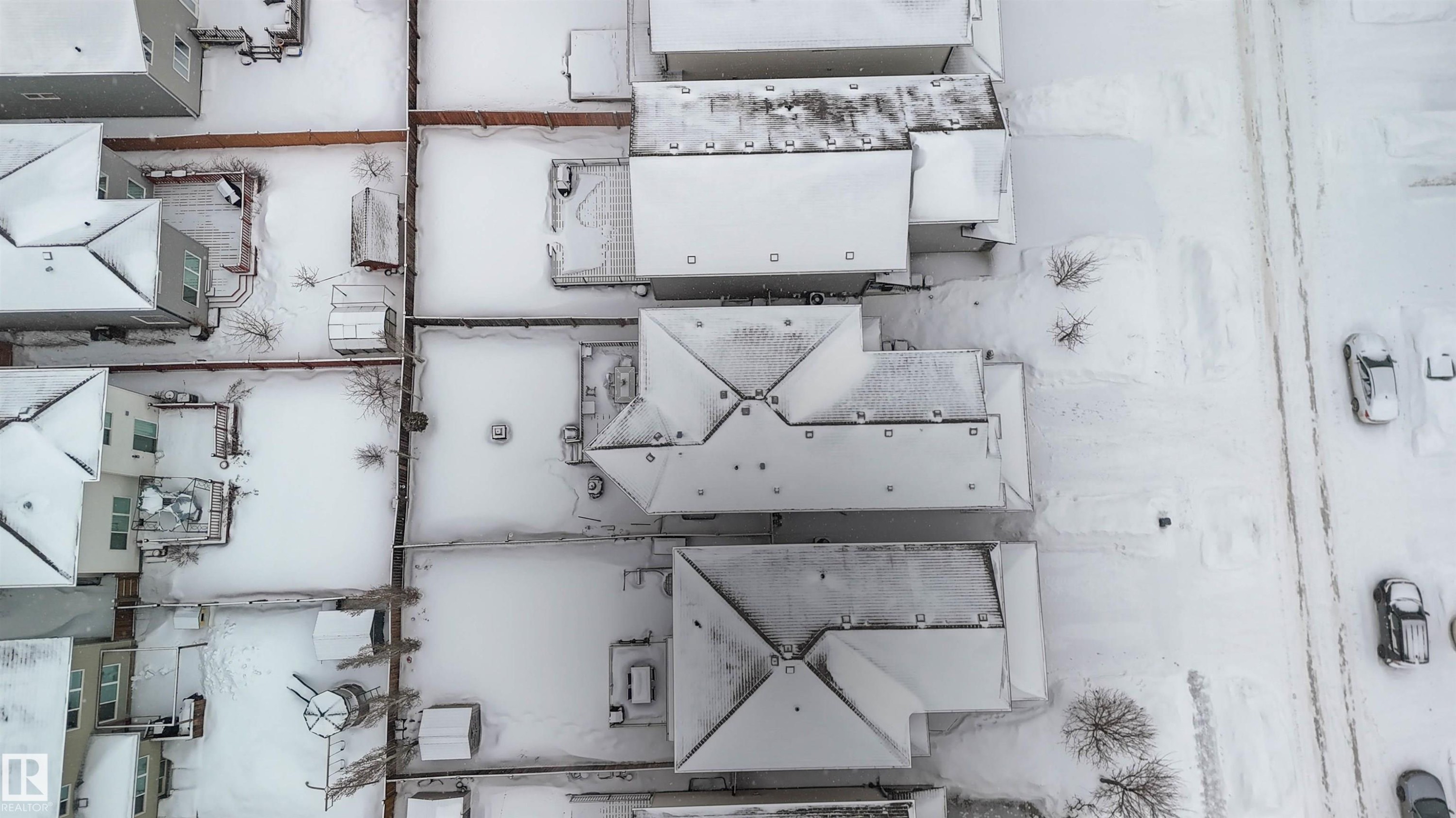 Aerial view showcasing properties with snow-covered roofs and yards, featuring a visible road with parked vehicles - 12232 167B Avenue, Edmonton, AB -