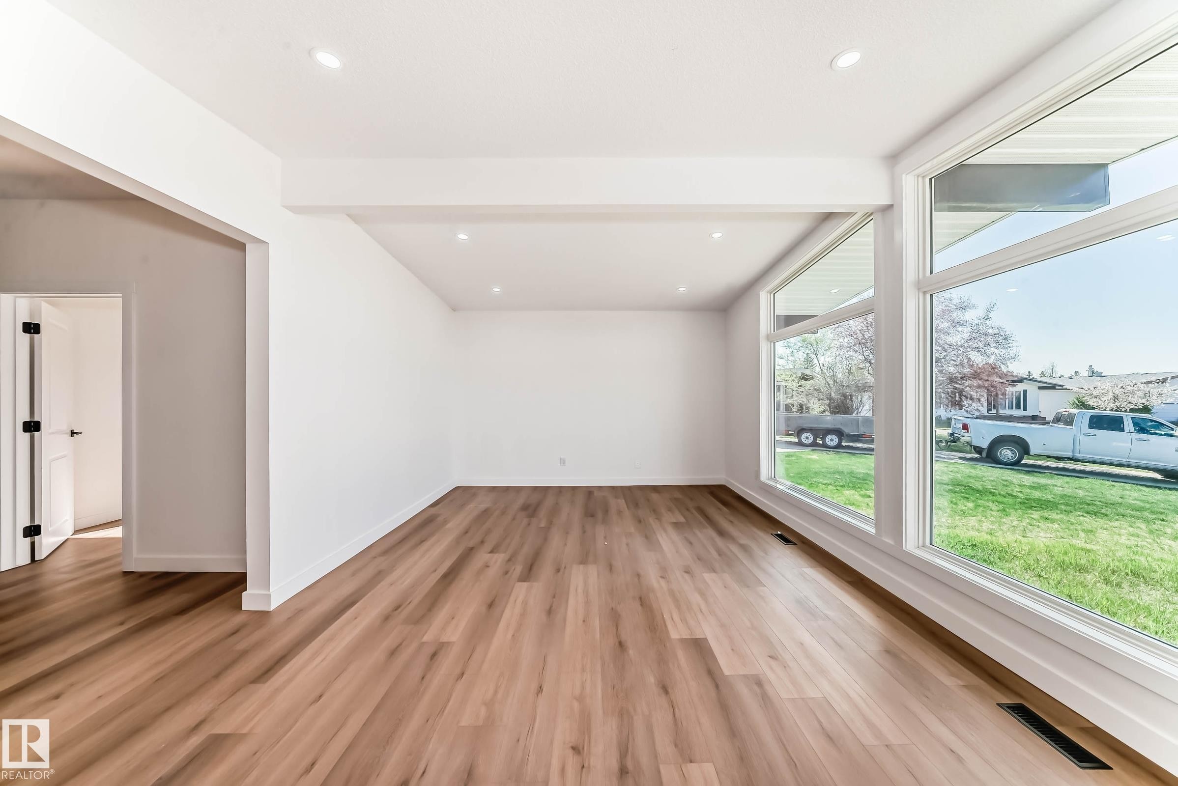 Spacious living area featuring large windows providing natural light, recessed lighting, and wood-style flooring - 7220 152A Ave, Edmonton, AB - Indoor Photo Showing Other Room