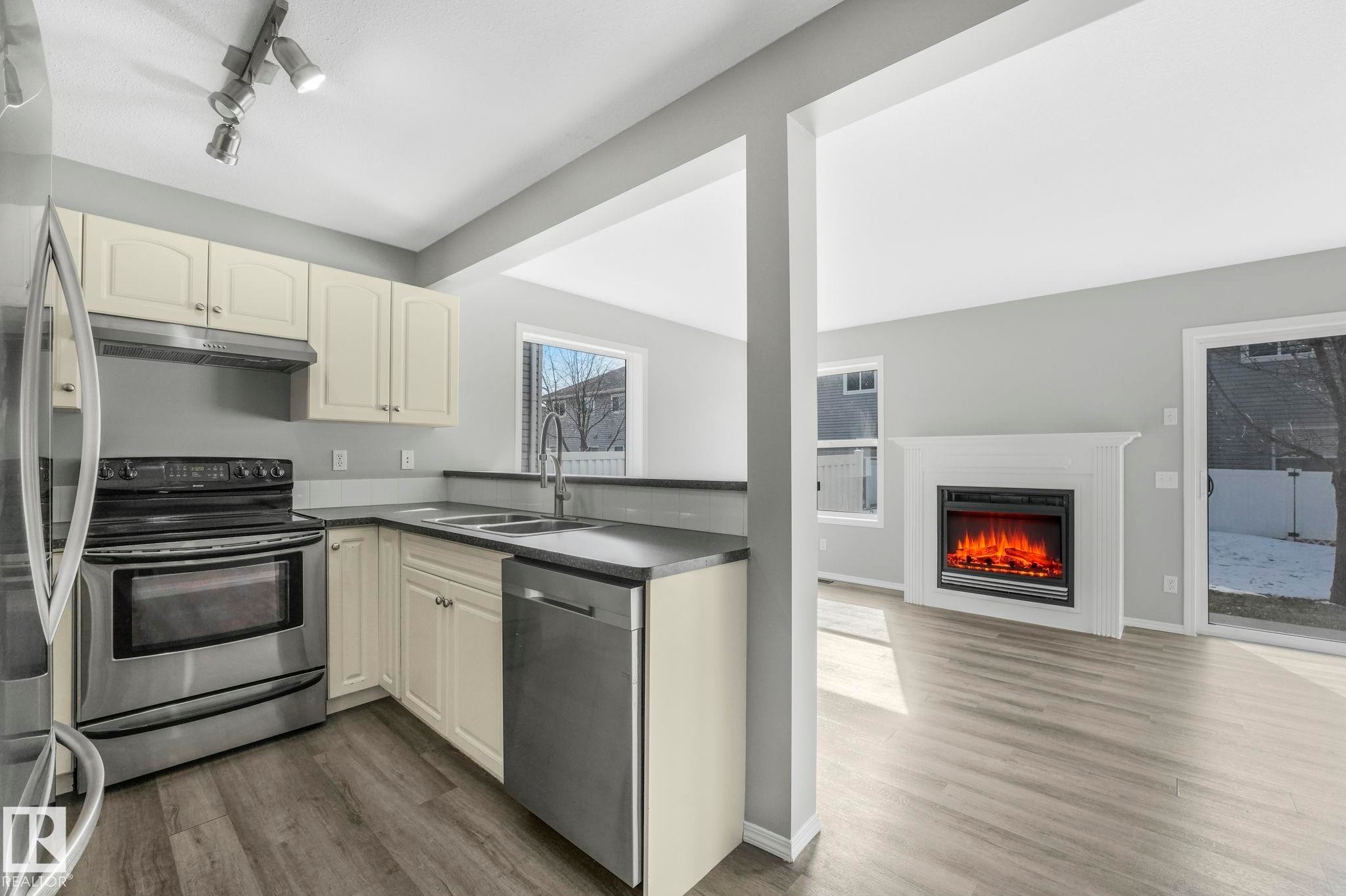 The property features a kitchen with light-colored cabinetry, stainless steel appliances, and a double basin sink - 123 230 Edwards Drive, Edmonton, AB - Indoor Photo Showing Kitchen With Double Sink