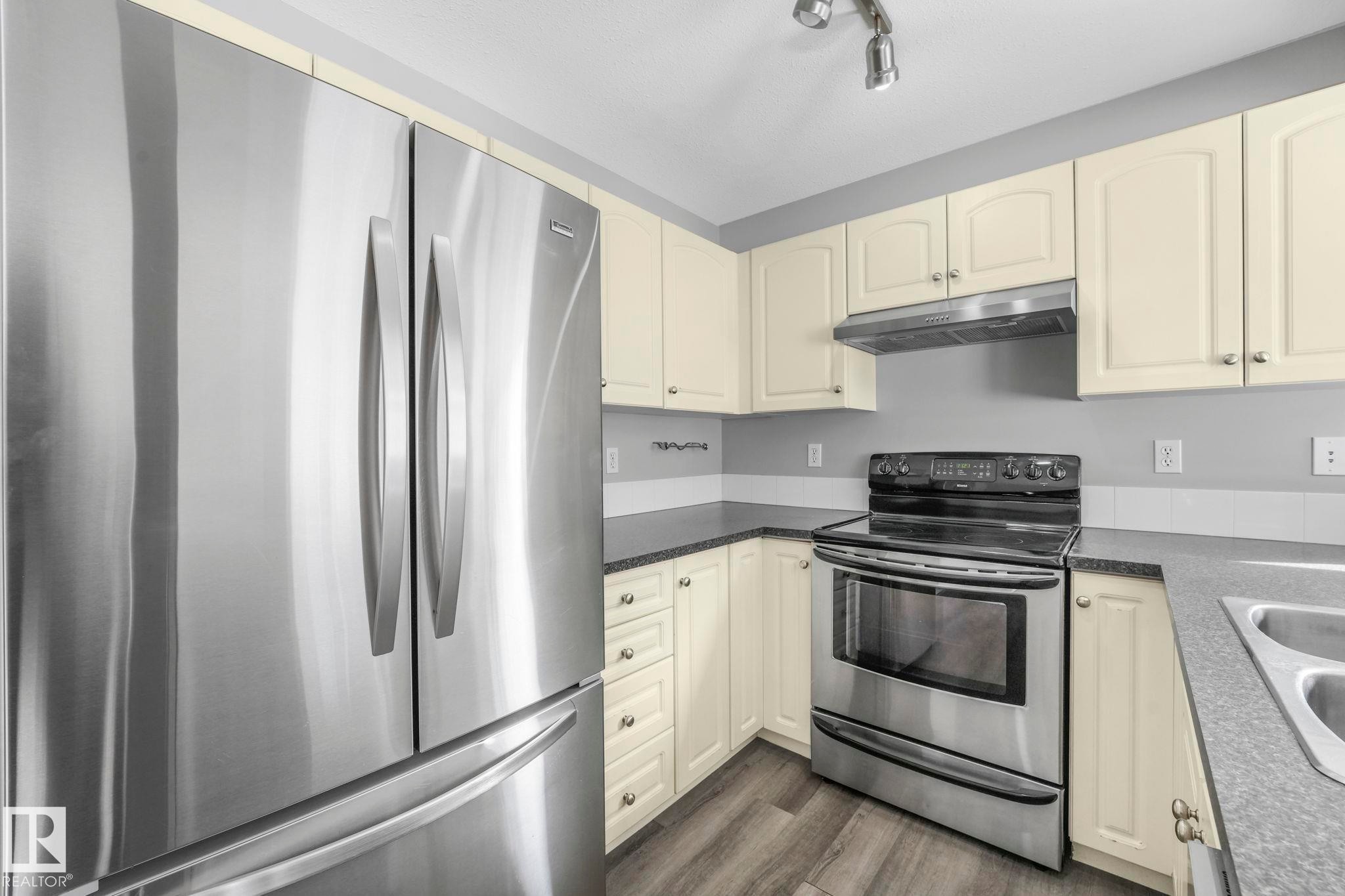 The kitchen features stainless steel appliances, including a side-by-side refrigerator and an oven with a range hood - 123 230 Edwards Drive, Edmonton, AB - Indoor Photo Showing Kitchen