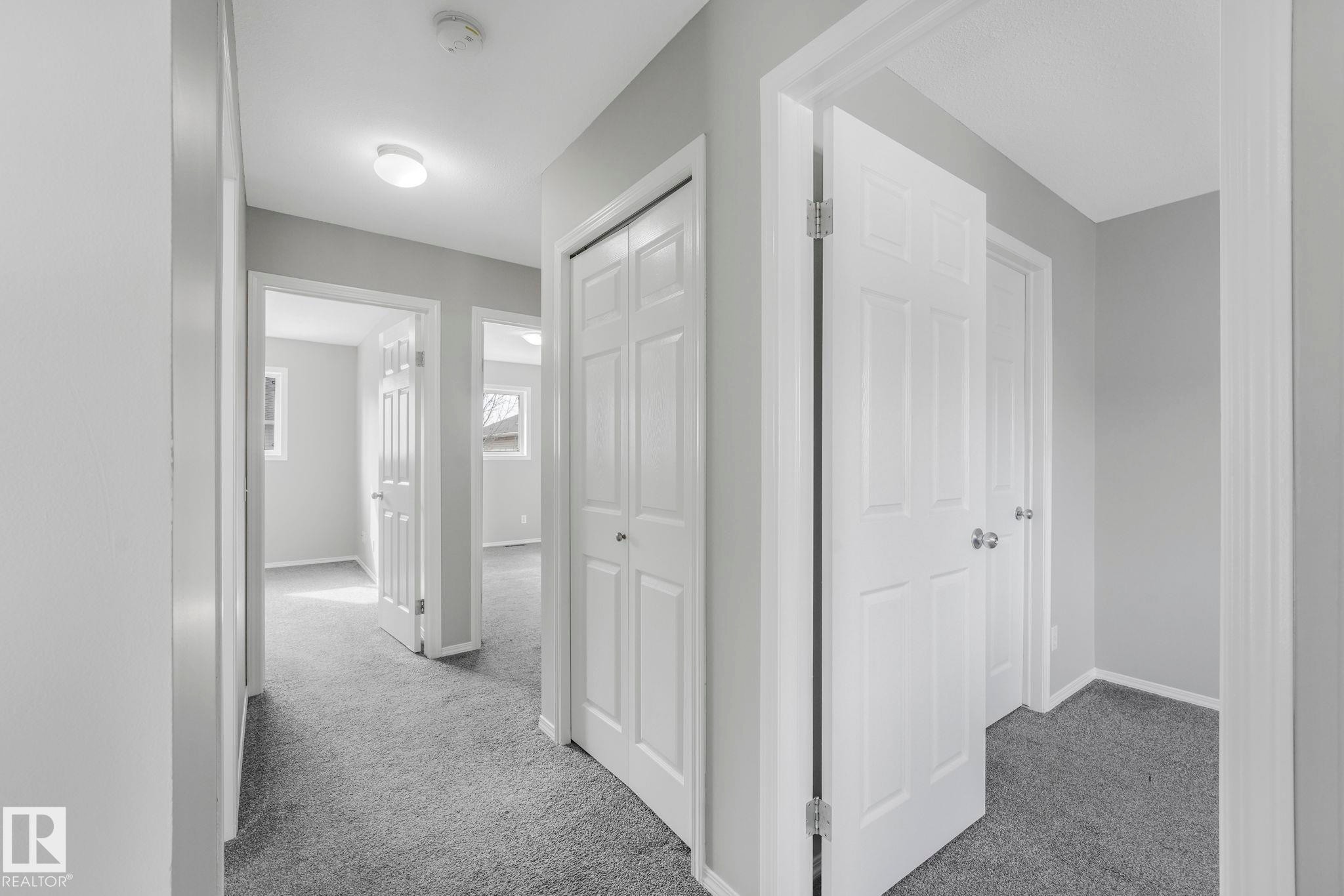 The property features a hallway with carpeted flooring and light grey walls - 123 230 Edwards Drive, Edmonton, AB - Indoor Photo Showing Other Room