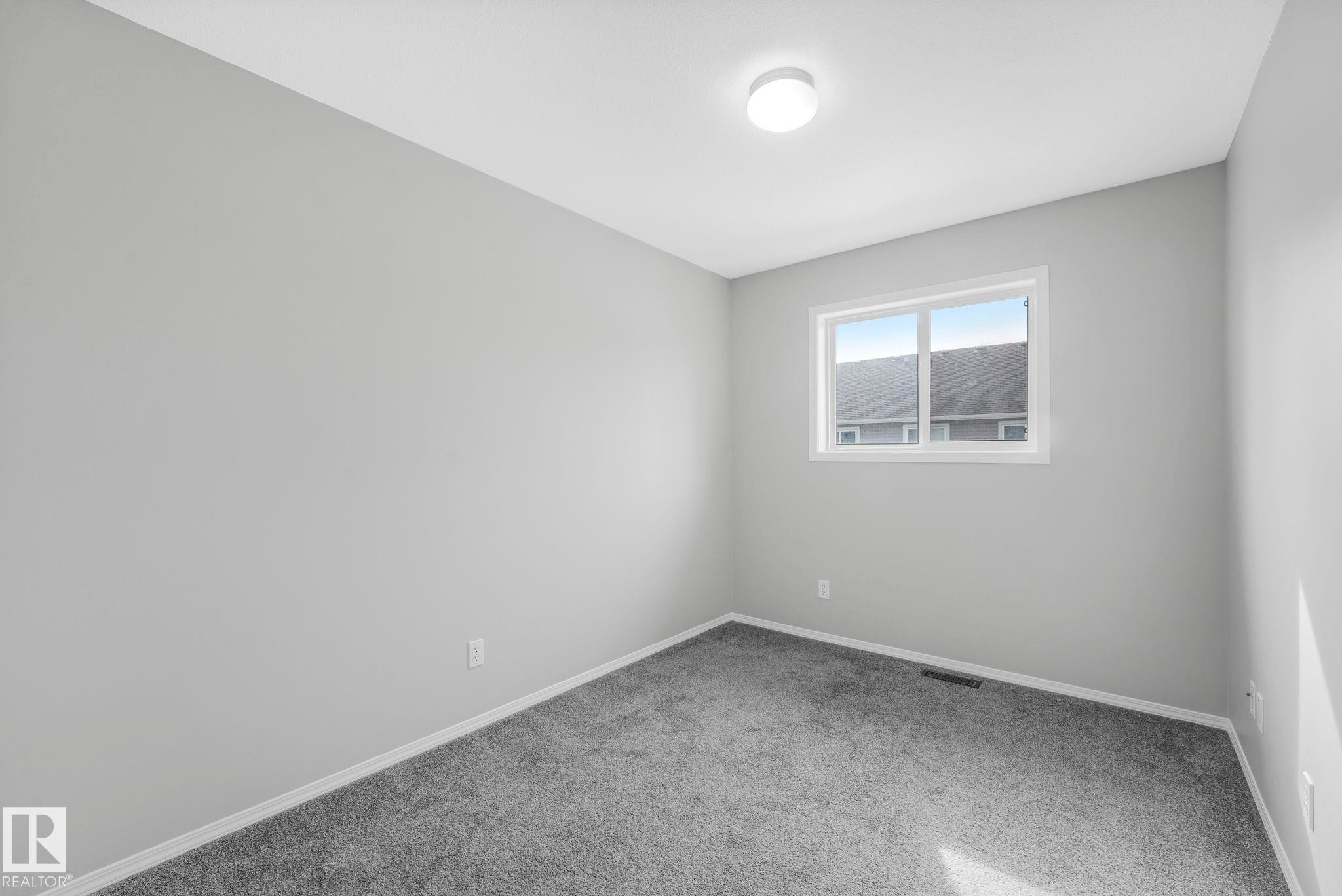 The room features light gray walls, gray carpeting, a single window, and a ceiling-mounted light fixture - 123 230 Edwards Drive, Edmonton, AB - Indoor Photo Showing Other Room