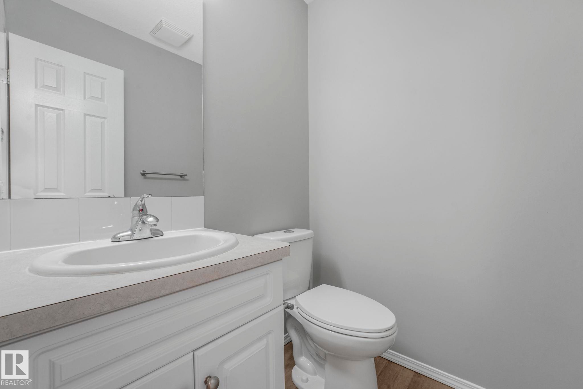 Bathroom featuring a white vanity with a built-in sink, a toilet, and light gray walls - 123 230 Edwards Drive, Edmonton, AB - Indoor Photo Showing Bathroom