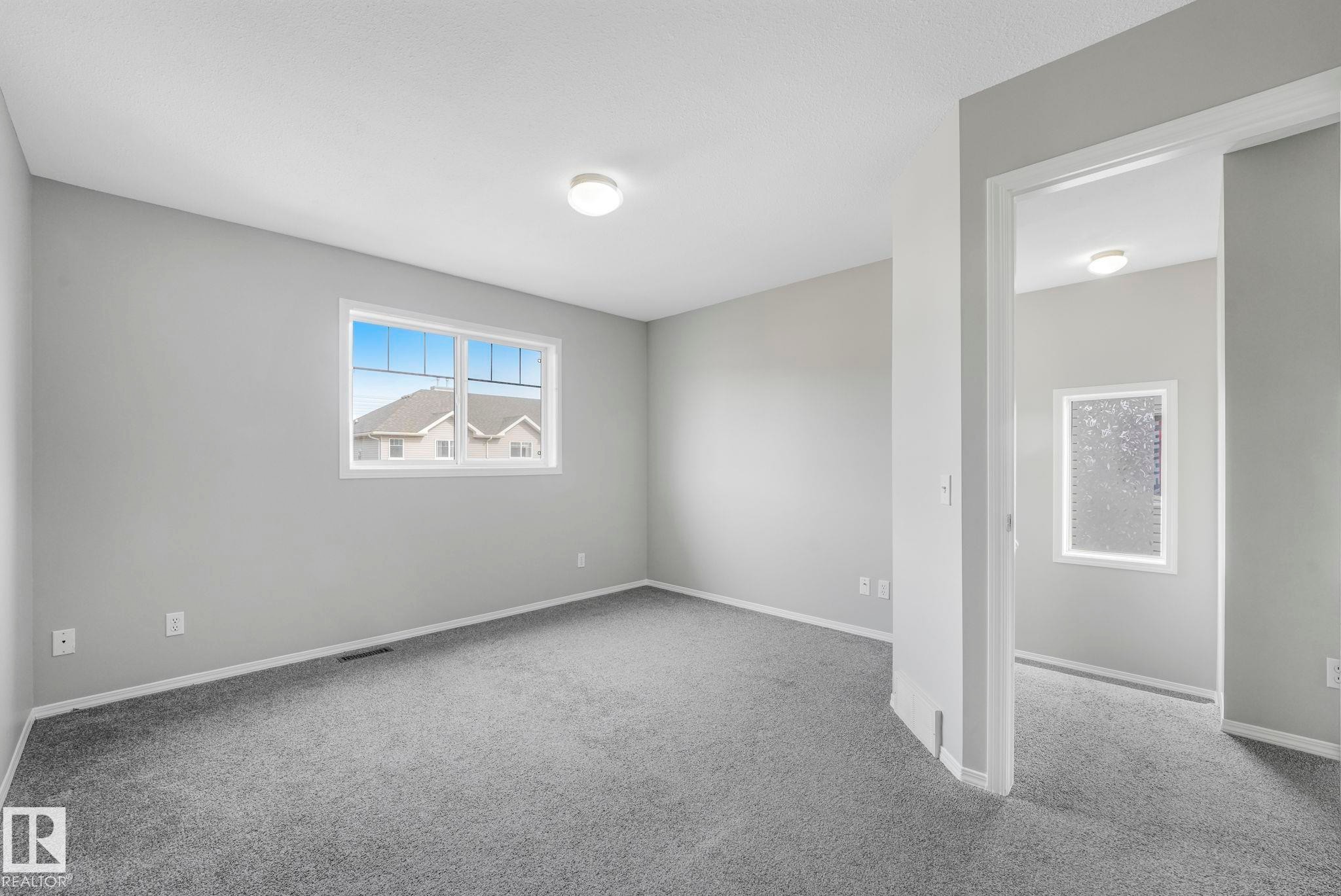 This room features neutral gray walls and gray carpeting, creating a versatile aesthetic - 123 230 Edwards Drive, Edmonton, AB - Indoor Photo Showing Other Room