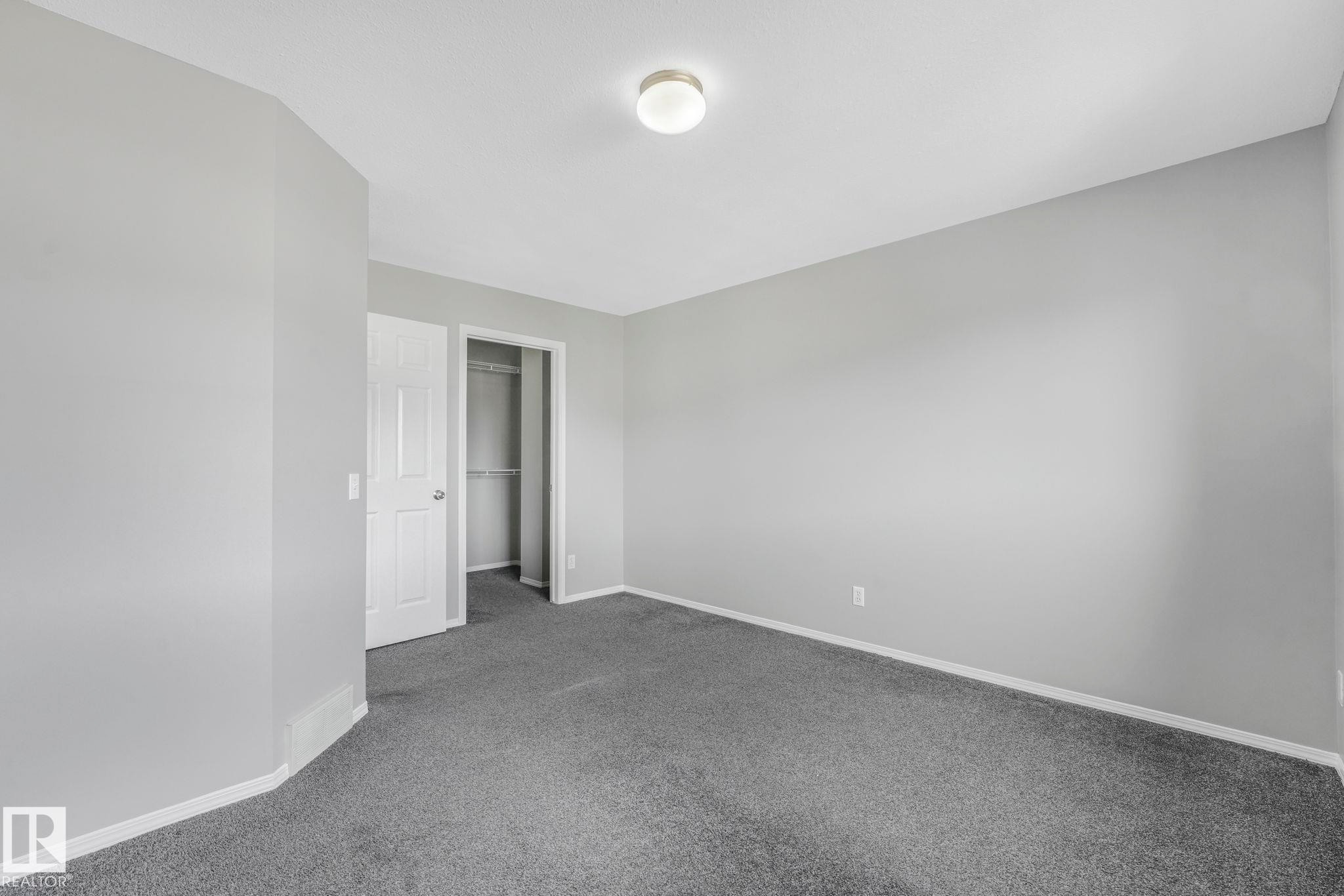 This room features light gray painted walls, dark gray carpeting, and white baseboards - 123 230 Edwards Drive, Edmonton, AB - Indoor Photo Showing Other Room