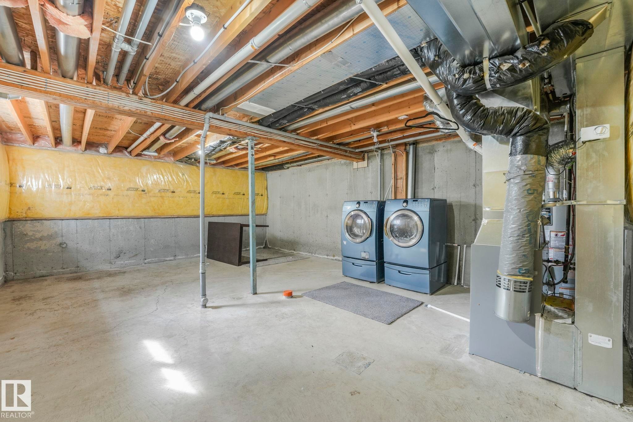 The property features an unfinished basement with exposed wooden joists and concrete walls, providing an expansive area for potential customization - 123 230 Edwards Drive, Edmonton, AB - Indoor Photo Showing Basement