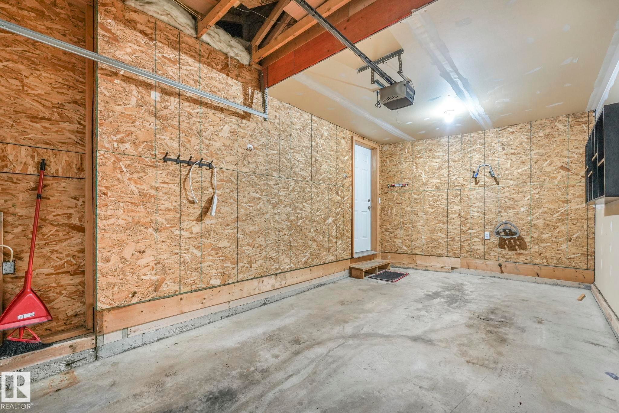 The property features a garage with exposed wood framing and oriented strand board walls - 123 230 Edwards Drive, Edmonton, AB - Indoor