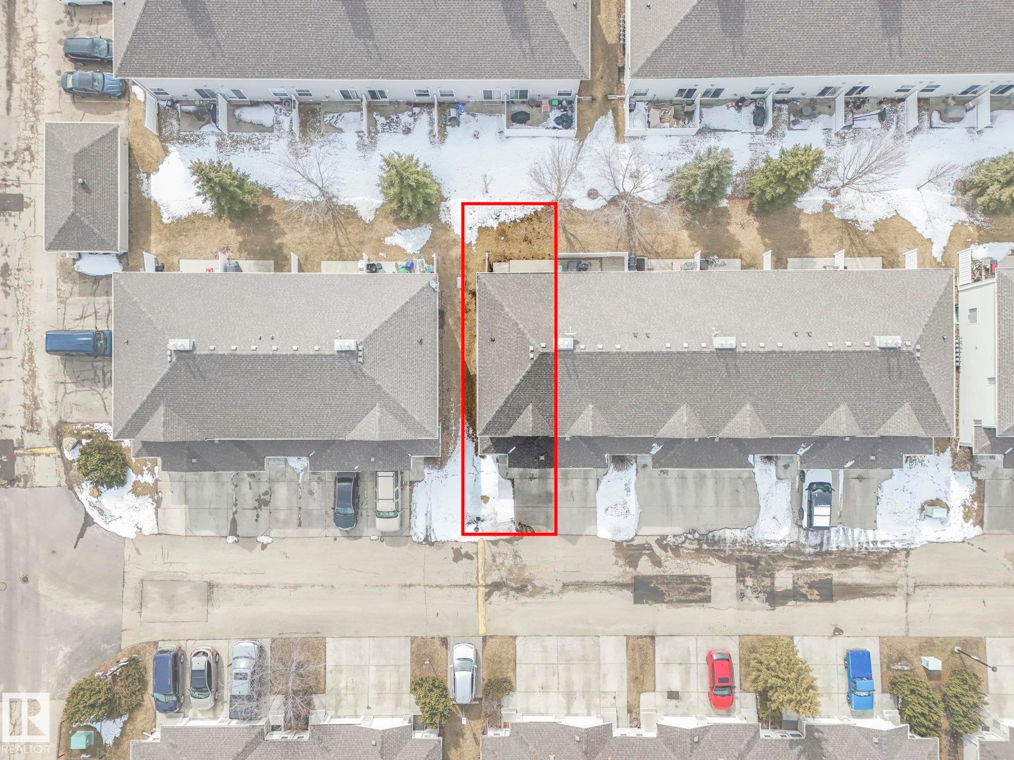 Aerial view highlighting the property's roofline, surrounding paved areas, and green spaces with scattered trees - 123 230 Edwards Drive, Edmonton, AB - Other