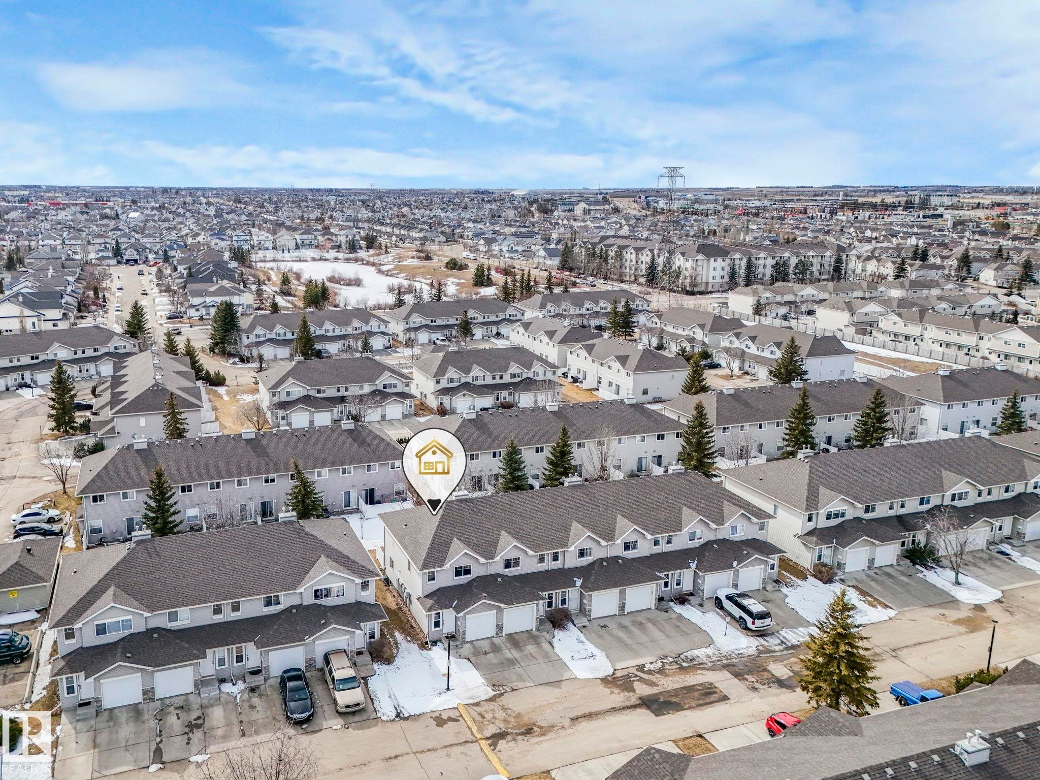 Aerial view of the property and surrounding residential neighborhood, featuring rows of townhomes with attached garages and paved driveways - 123 230 Edwards Drive, Edmonton, AB - Outdoor With View