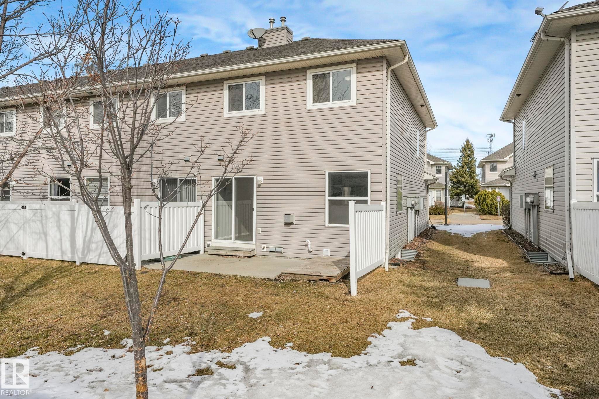 The property features a private fenced yard with a concrete patio - 123 230 Edwards Drive, Edmonton, AB - Outdoor With Exterior
