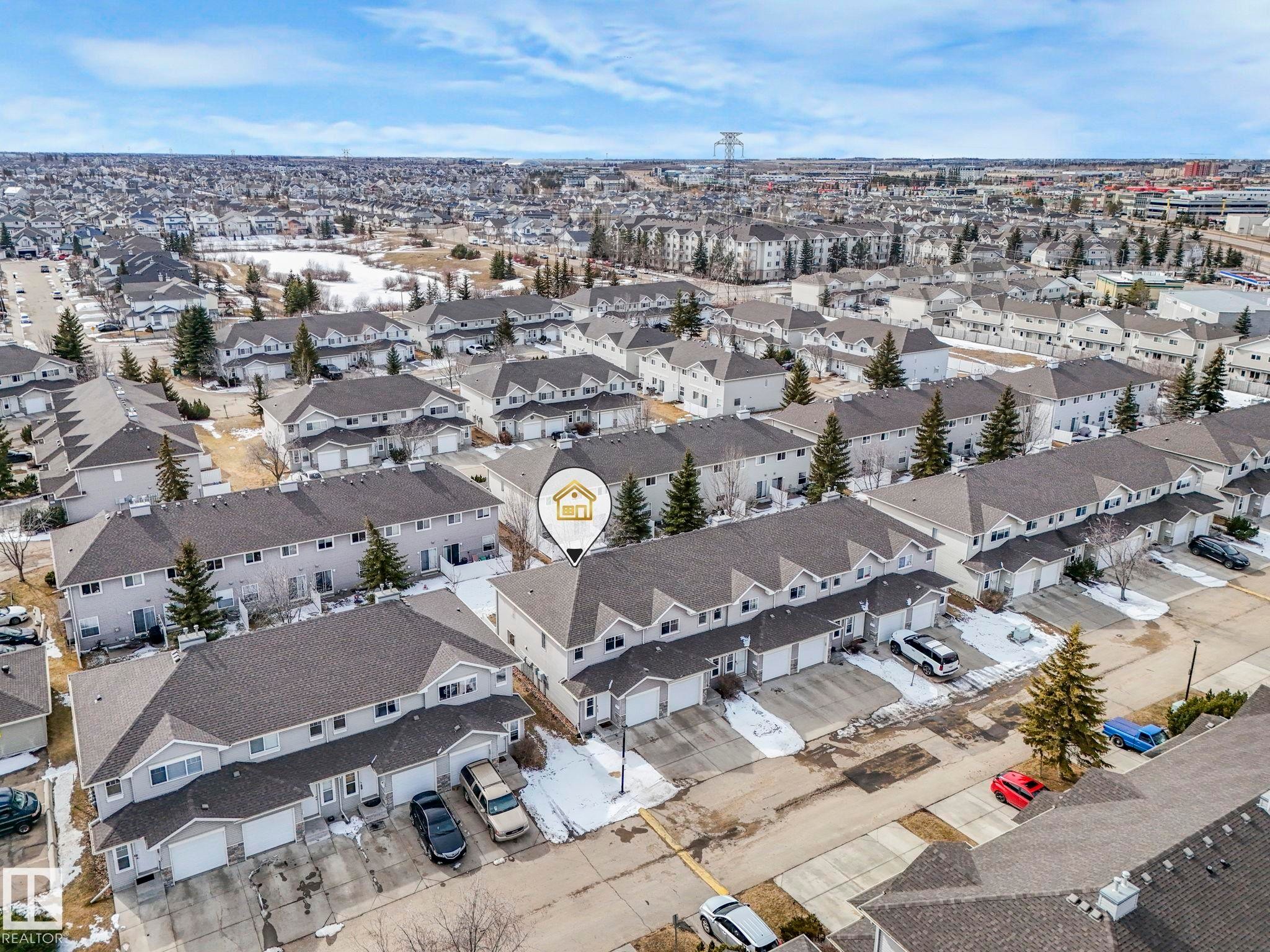 Aerial view showcasing the property within a residential setting, featuring townhomes with attached garages and surrounding greenery - 123 230 Edwards Drive, Edmonton, AB - Outdoor With View