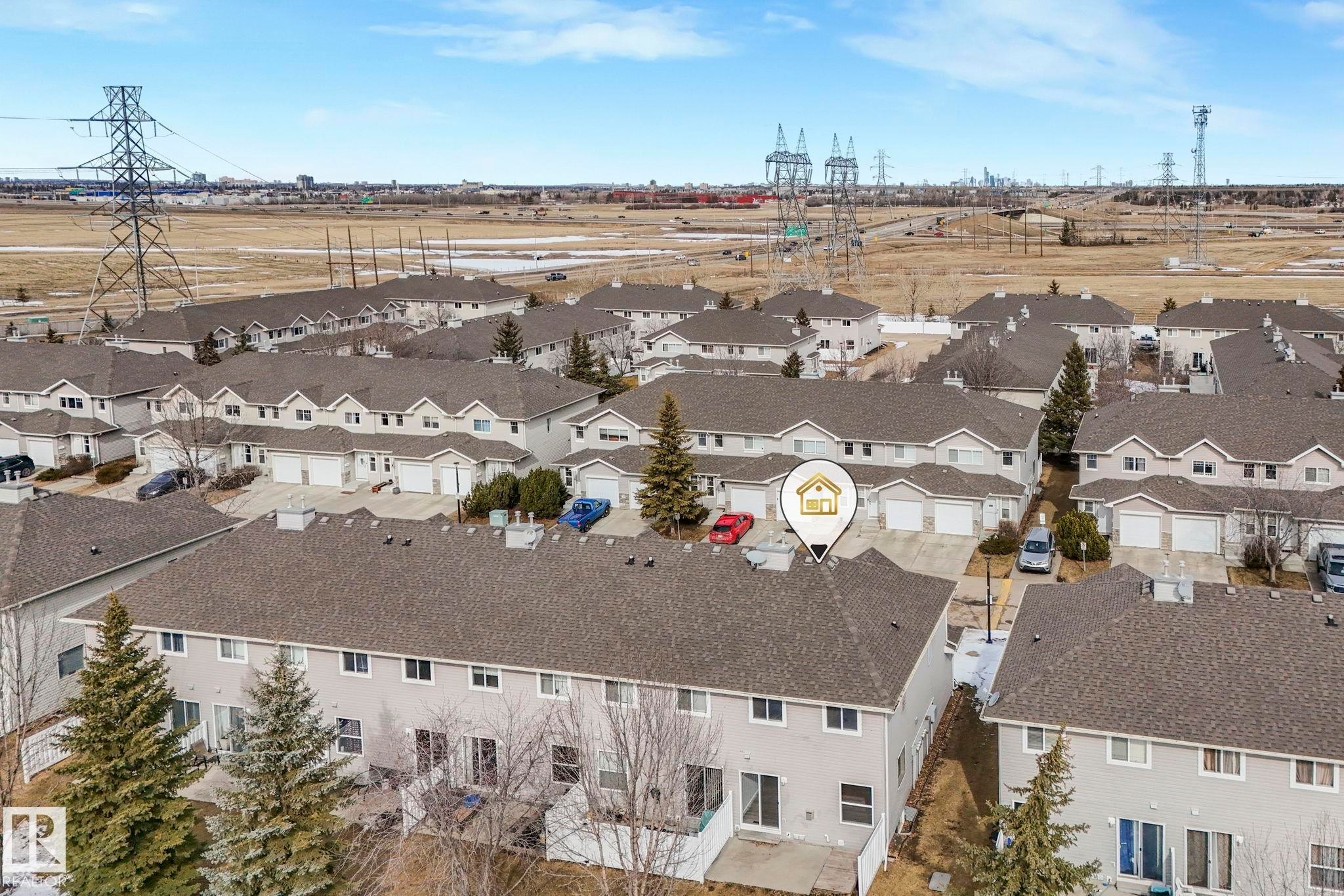 This aerial view showcases a property within a community of residences, each featuring a pitched roof - 123 230 Edwards Drive, Edmonton, AB - Outdoor With View