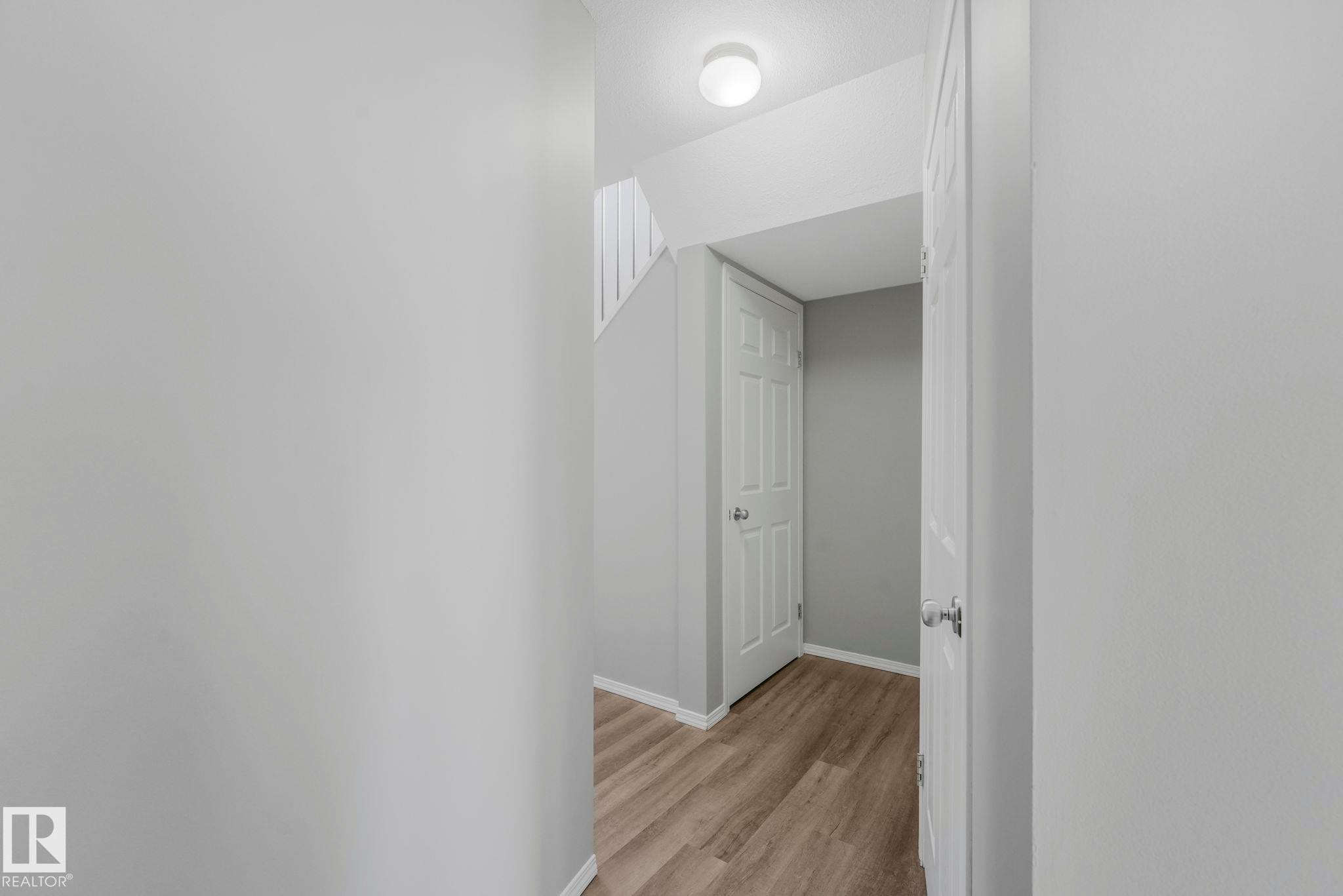 Entryway featuring light wood-look flooring and white paneled doors - 123 230 Edwards Drive, Edmonton, AB - Indoor Photo Showing Other Room