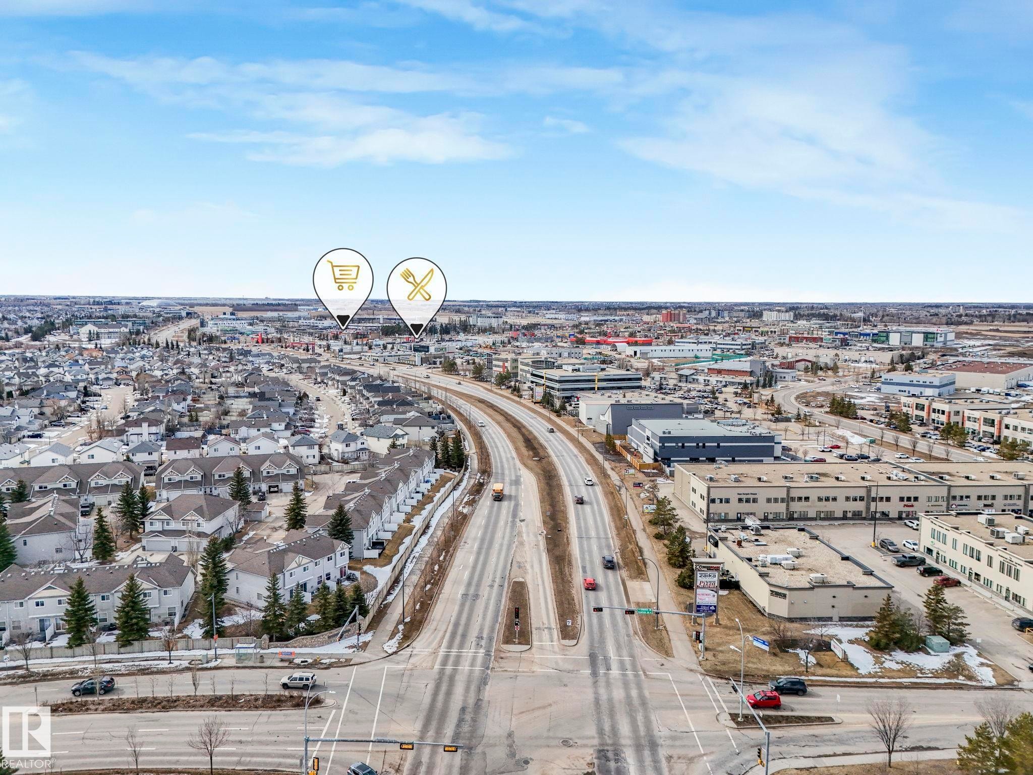 Aerial view of the surrounding neighborhood, featuring residential properties, commercial buildings, and a multi-lane road - 123 230 Edwards Drive, Edmonton, AB - Outdoor With View