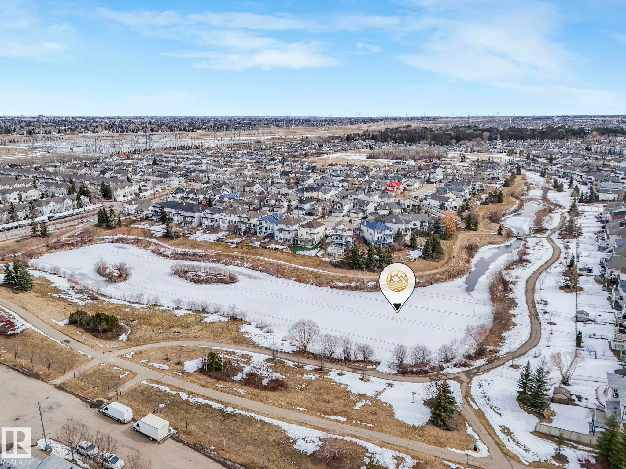 Aerial view showcasing the surrounding neighborhood, featuring residential properties, a frozen pond, and walking paths - 123 230 Edwards Drive, Edmonton, AB - Outdoor With View