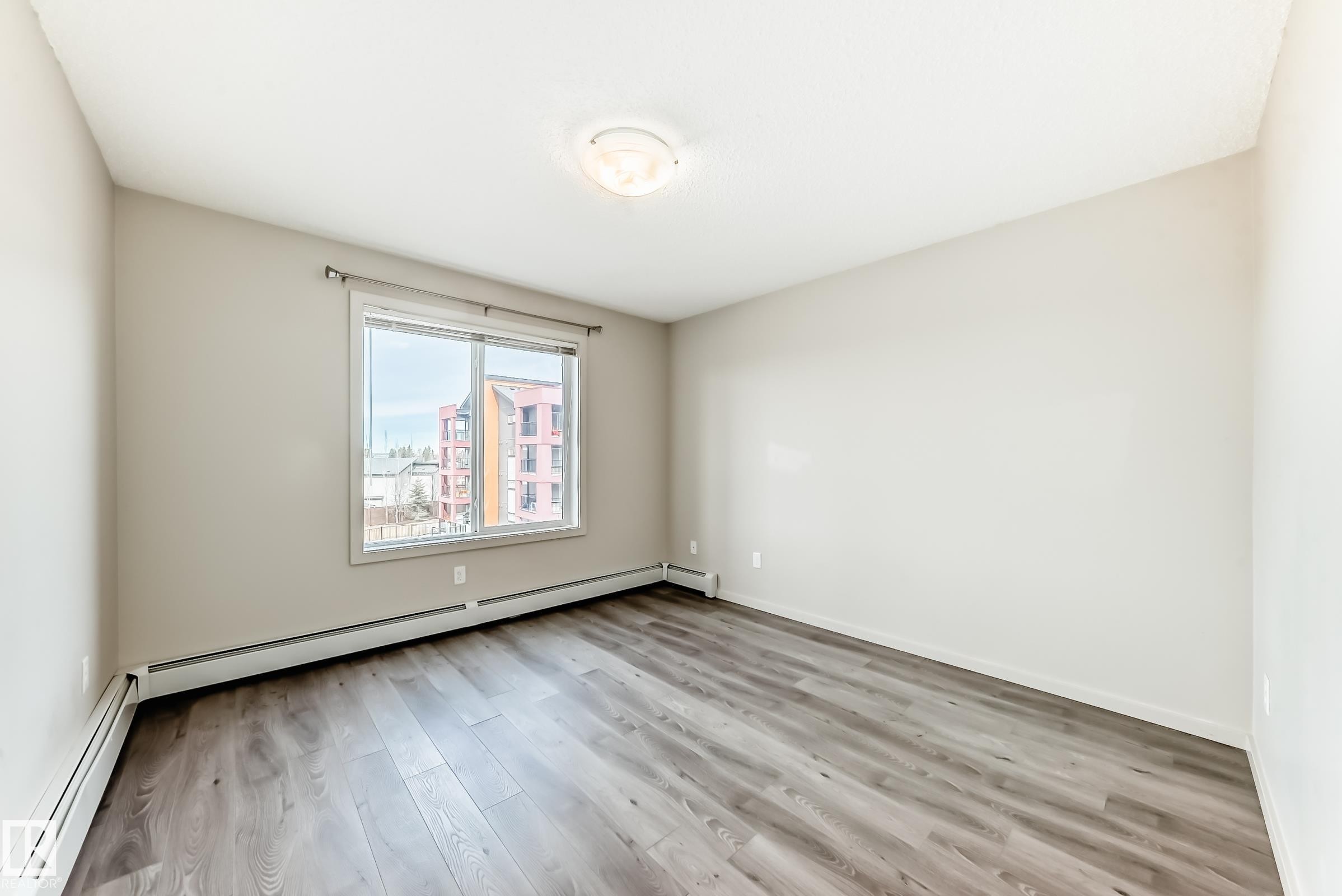 This room features light-colored walls and a window providing a view of buildings - 332 344 Windermere Road, Edmonton, AB - Indoor Photo Showing Other Room