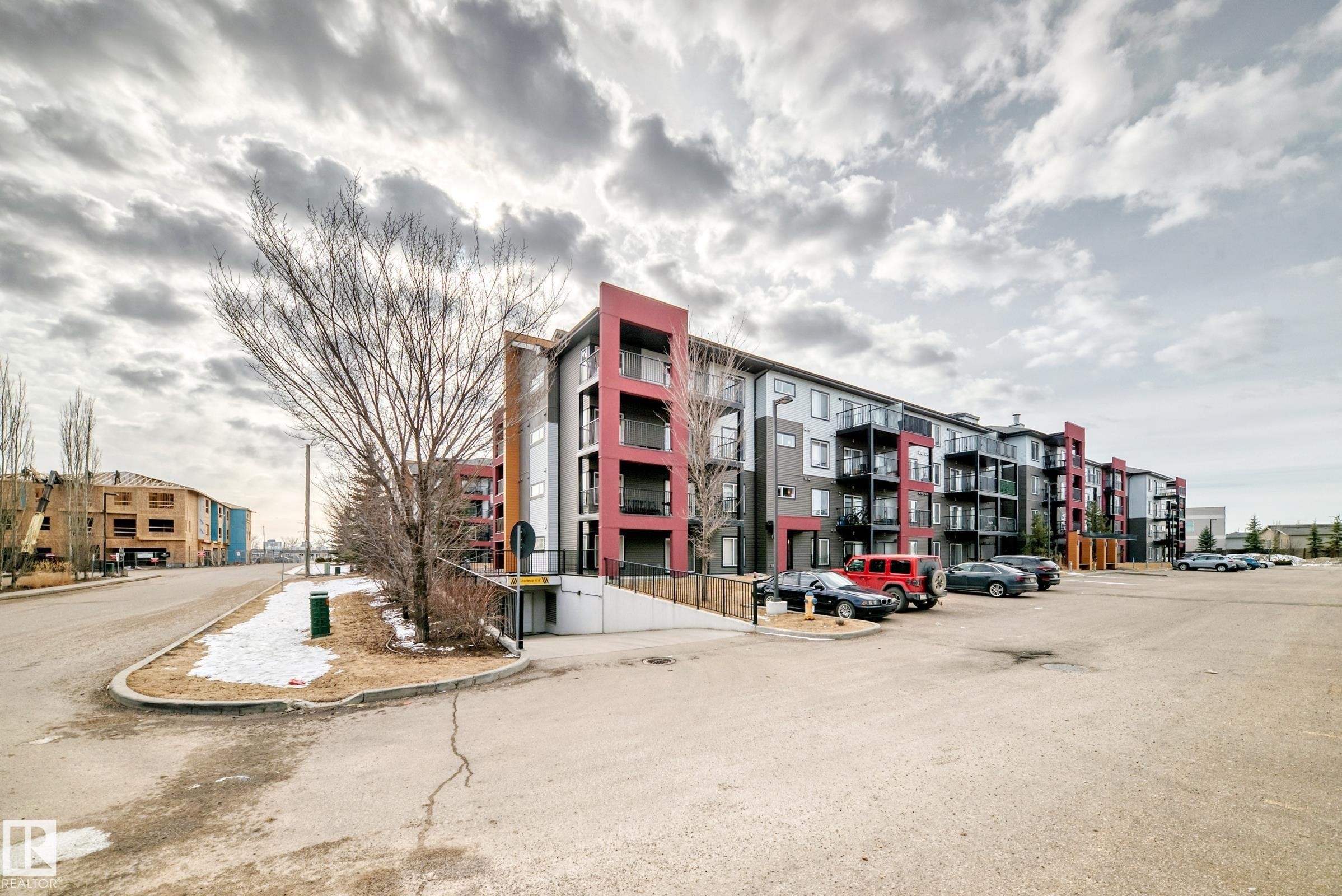The property features a multi-story building with a modern exterior design, incorporating red and grey cladding - 332 344 Windermere Road, Edmonton, AB - Outdoor With Balcony