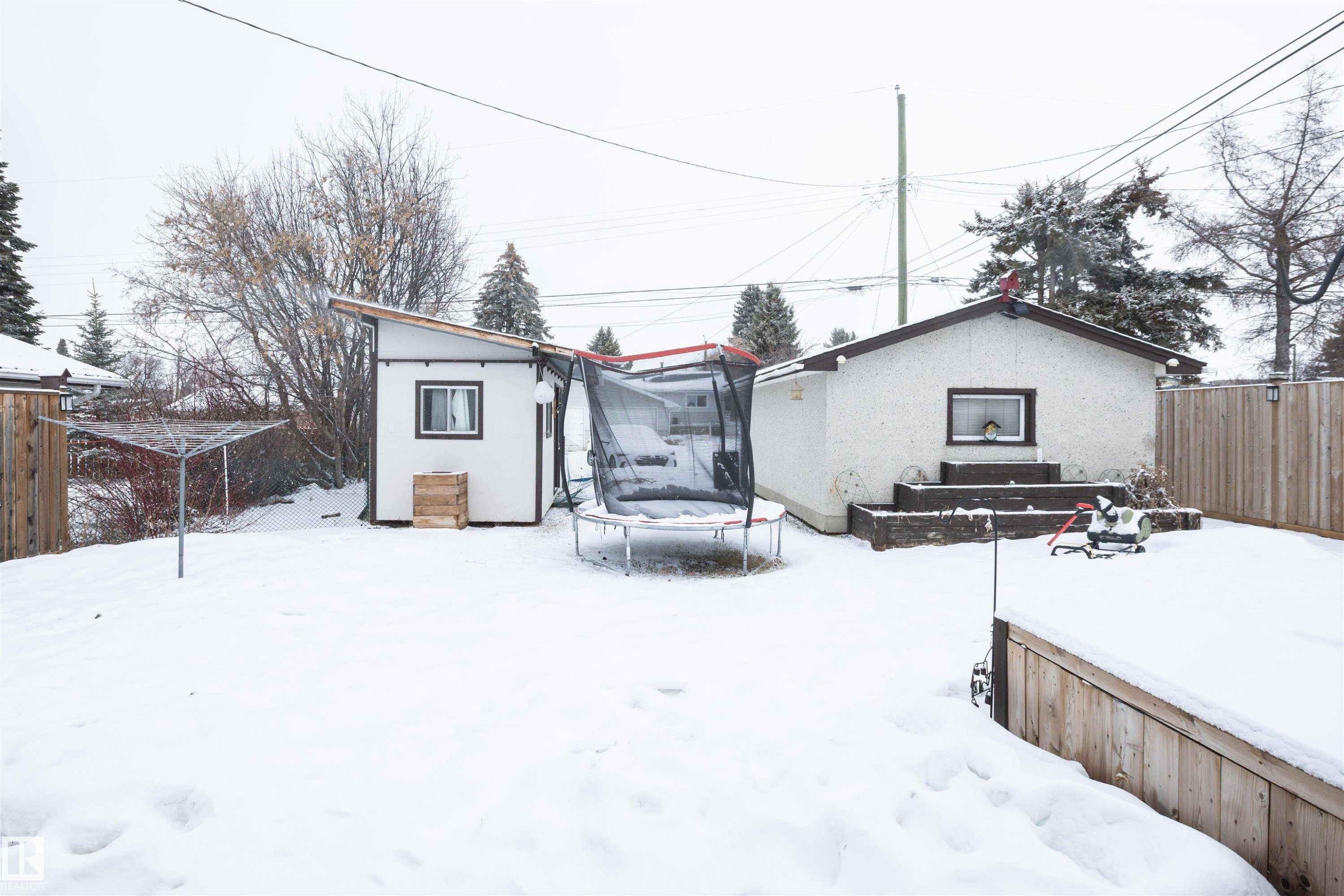 The property features a spacious backyard with a lawn, a shed, and a detached building - 4420 56 Avenue, Barrhead, AB - Outdoor
