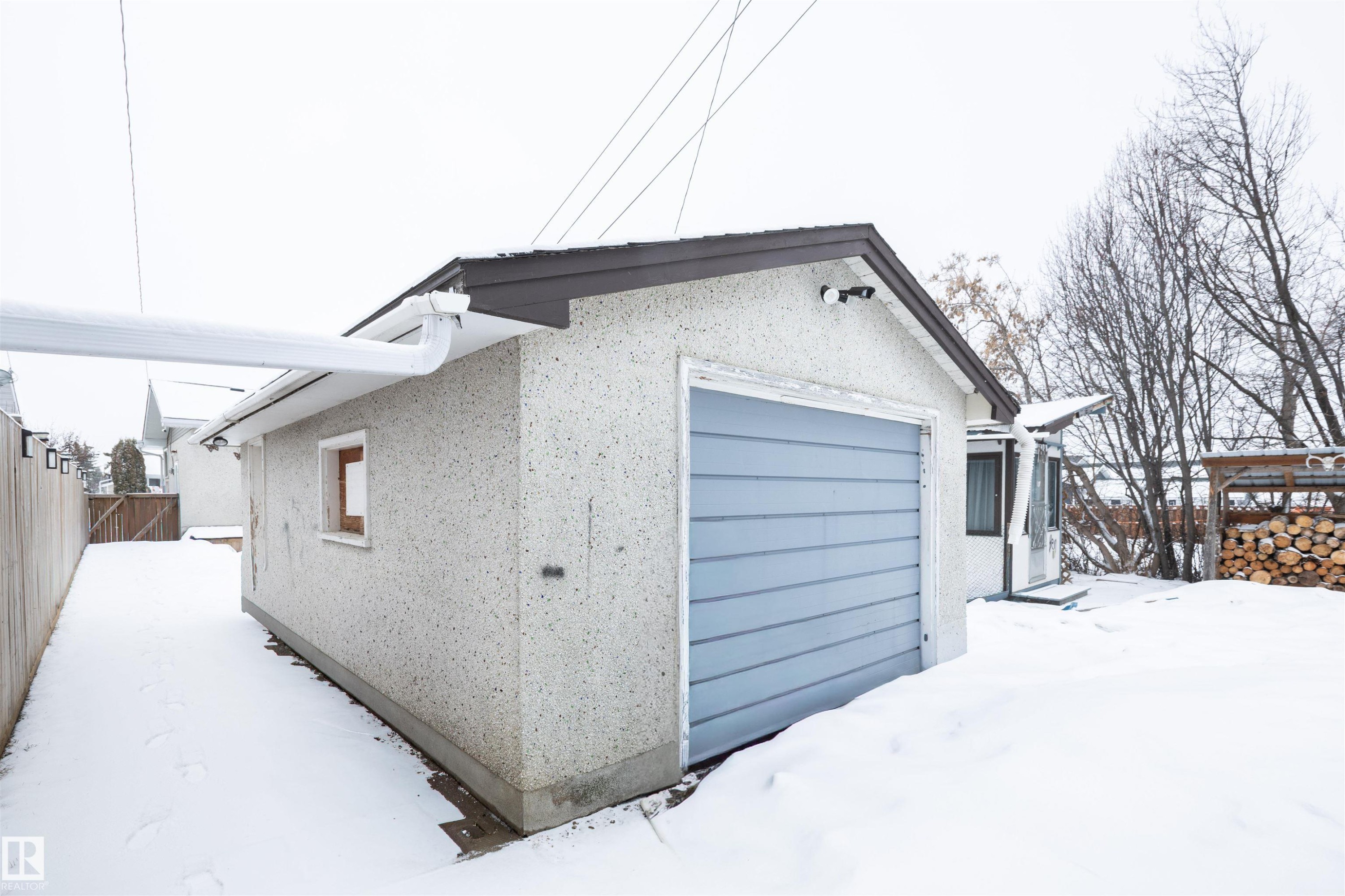 The property features a detached garage with a blue overhead door - 4420 56 Avenue, Barrhead, AB - Outdoor With Exterior