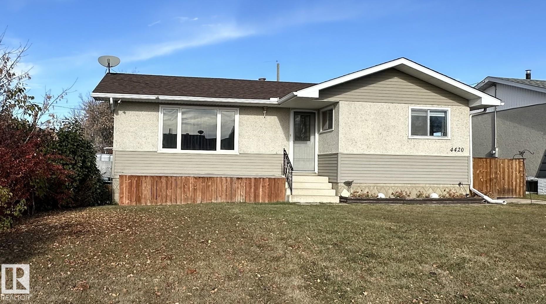 The property features a brown shingled roof, light-colored stucco, and horizontal siding - 4420 56 Avenue, Barrhead, AB - Outdoor
