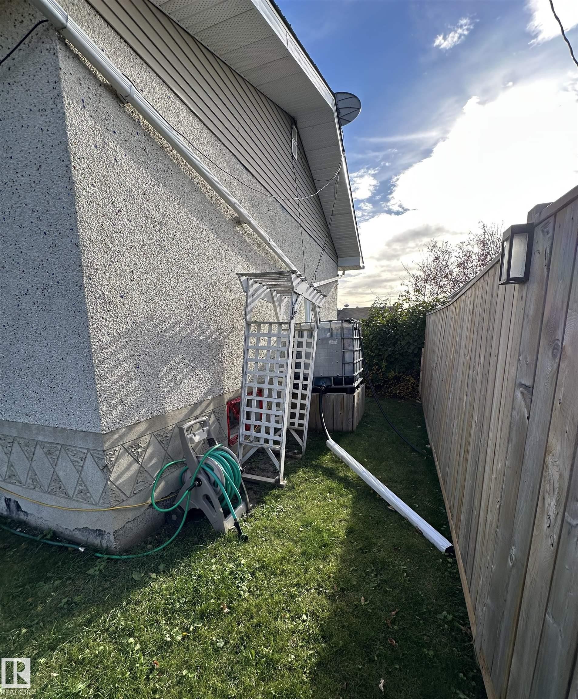 The property features exterior stucco siding and a well-maintained lawn area - 4420 56 Avenue, Barrhead, AB - Outdoor