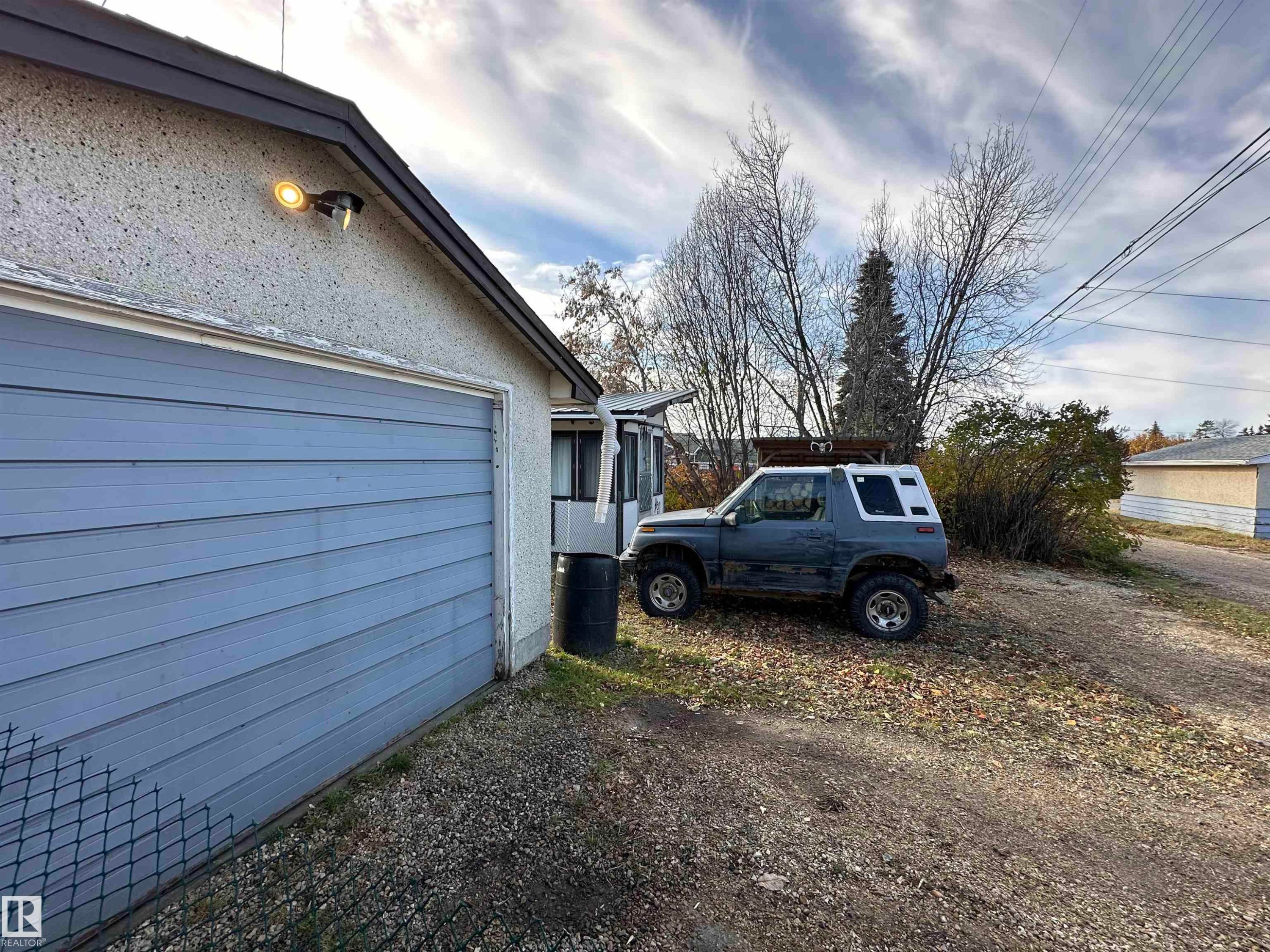The property features a garage with horizontal siding and an exterior light fixture - 4420 56 Avenue, Barrhead, AB - Outdoor