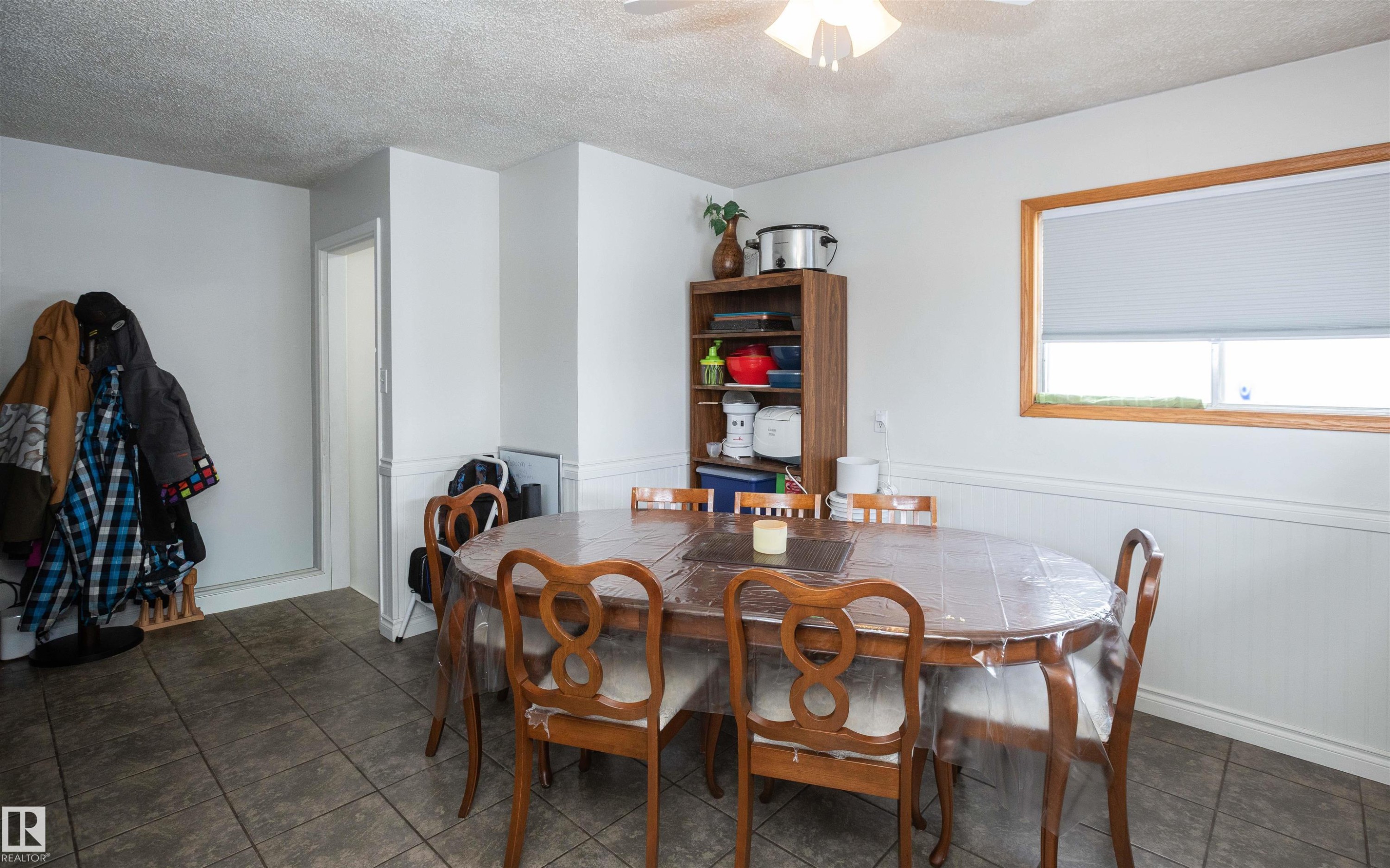 Dining area featuring tiled flooring, a window with a wood frame, and wainscoting - 4420 56 Avenue, Barrhead, AB - Indoor Photo Showing Dining Room