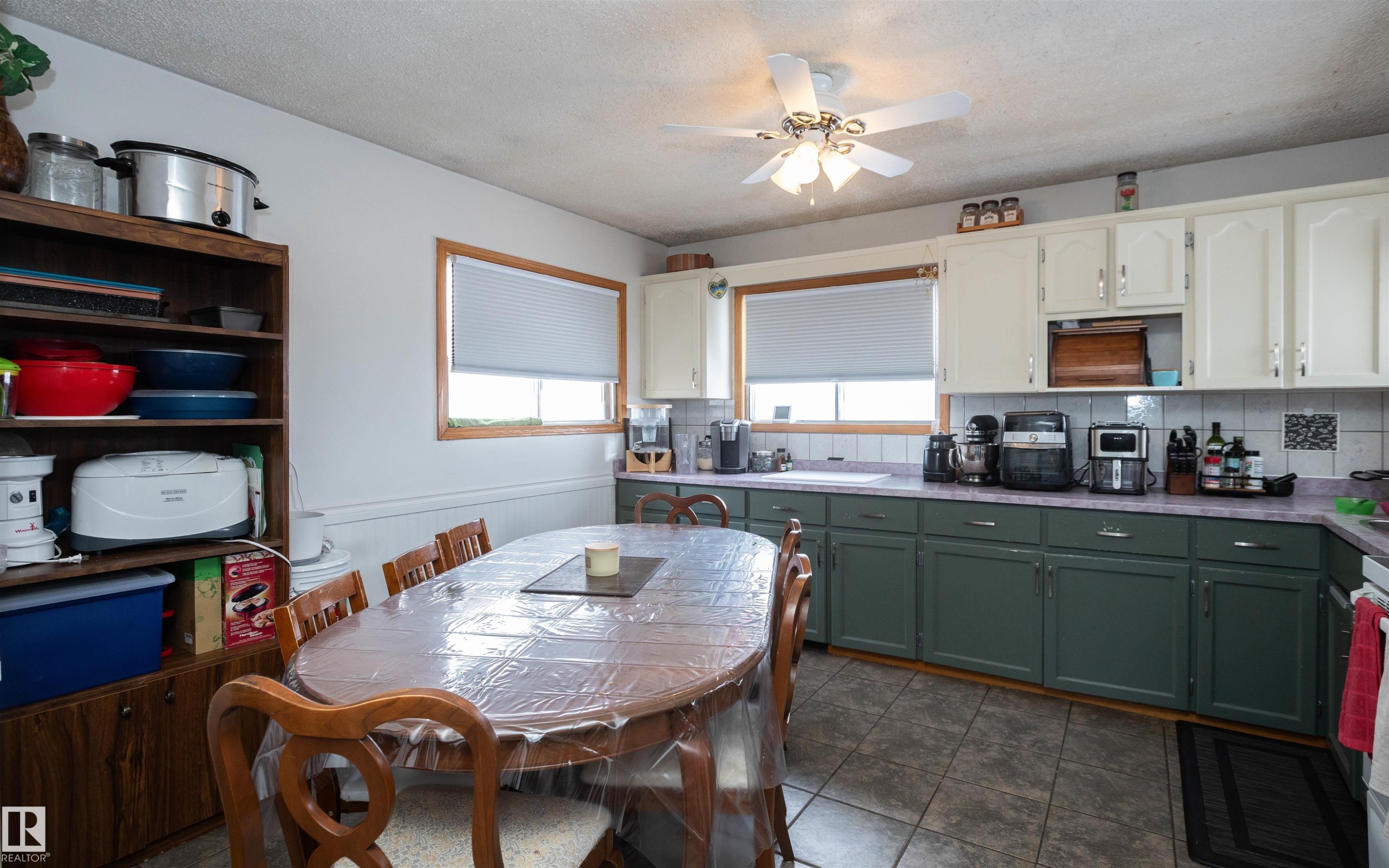 The kitchen features white upper cabinetry, dark green lower cabinetry, and a tiled backsplash - 4420 56 Avenue, Barrhead, AB - Indoor