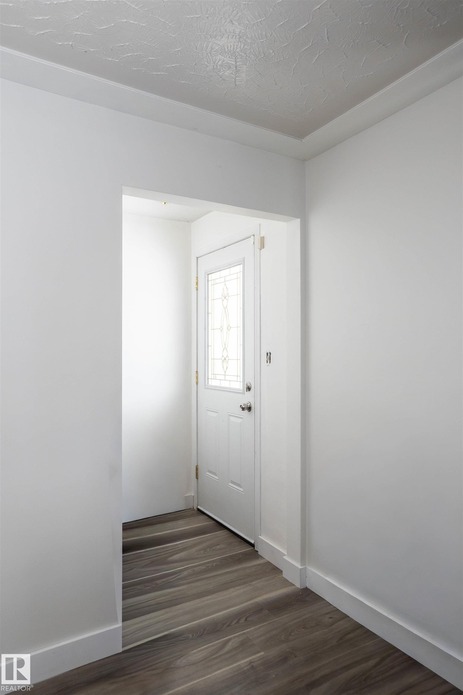 Entryway featuring a white door with decorative glass inserts and wood-look flooring - 4420 56 Avenue, Barrhead, AB - Indoor Photo Showing Other Room