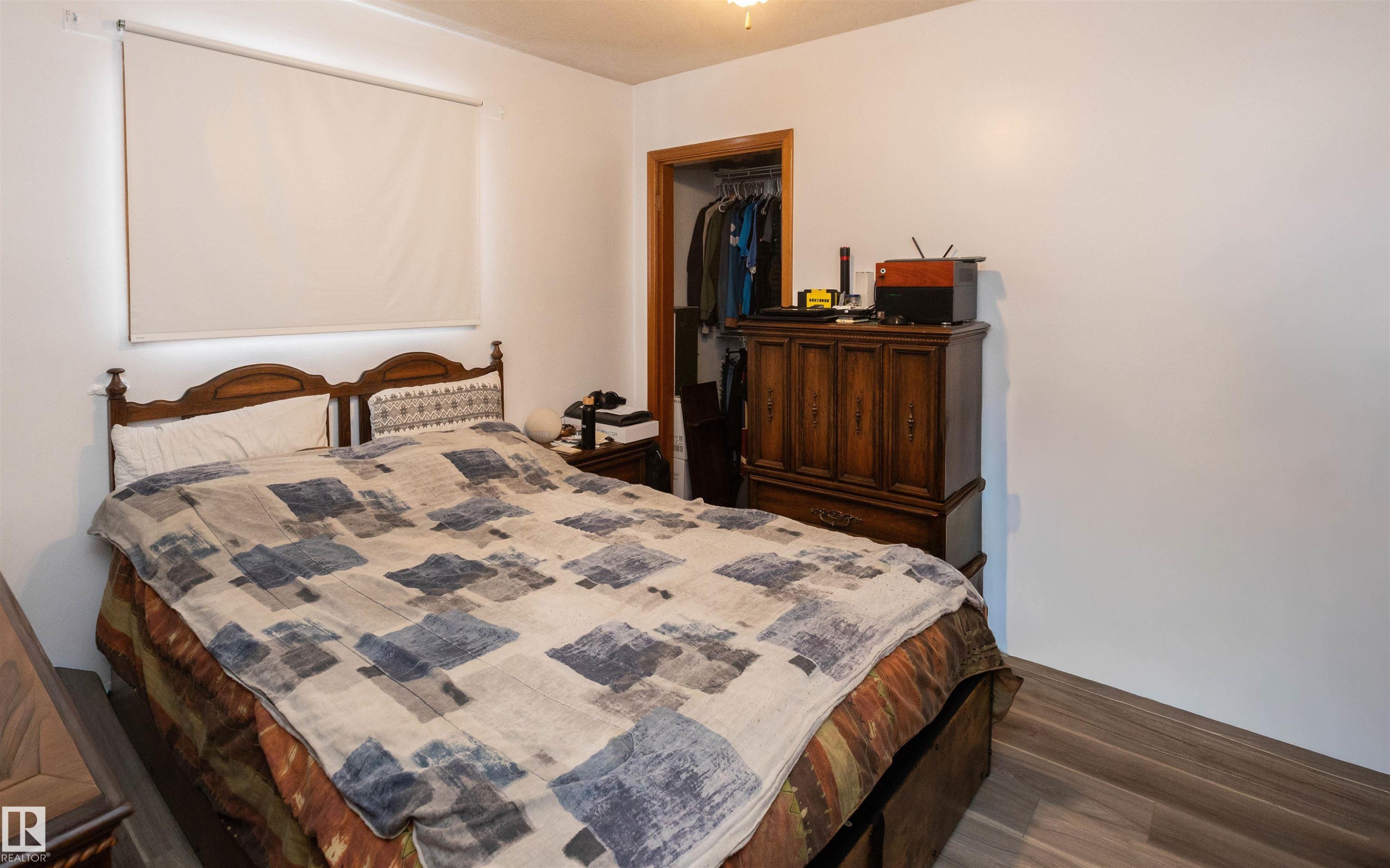 Bedroom featuring light-colored walls, wood-style flooring, and a window with a roller blind - 4420 56 Avenue, Barrhead, AB - Indoor Photo Showing Bedroom
