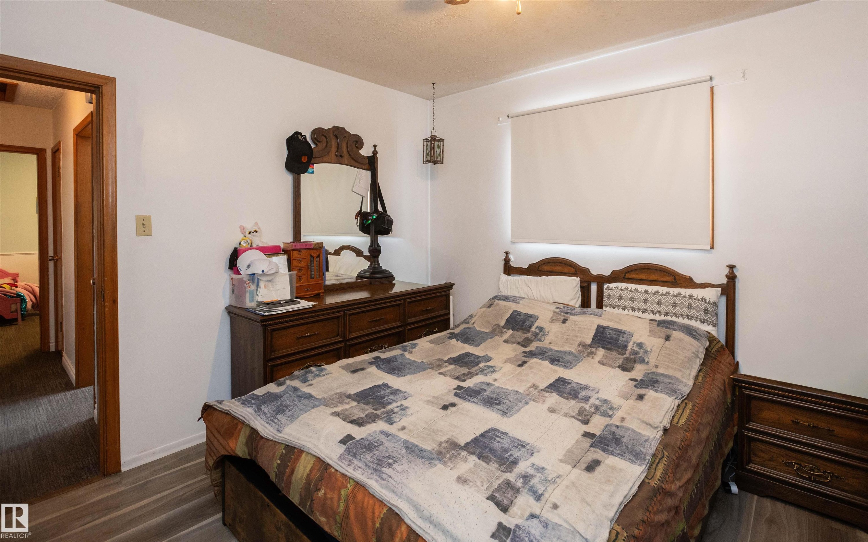 Bedroom featuring light-toned walls, a window with a roller shade, and wood-style flooring - 4420 56 Avenue, Barrhead, AB - Indoor Photo Showing Bedroom