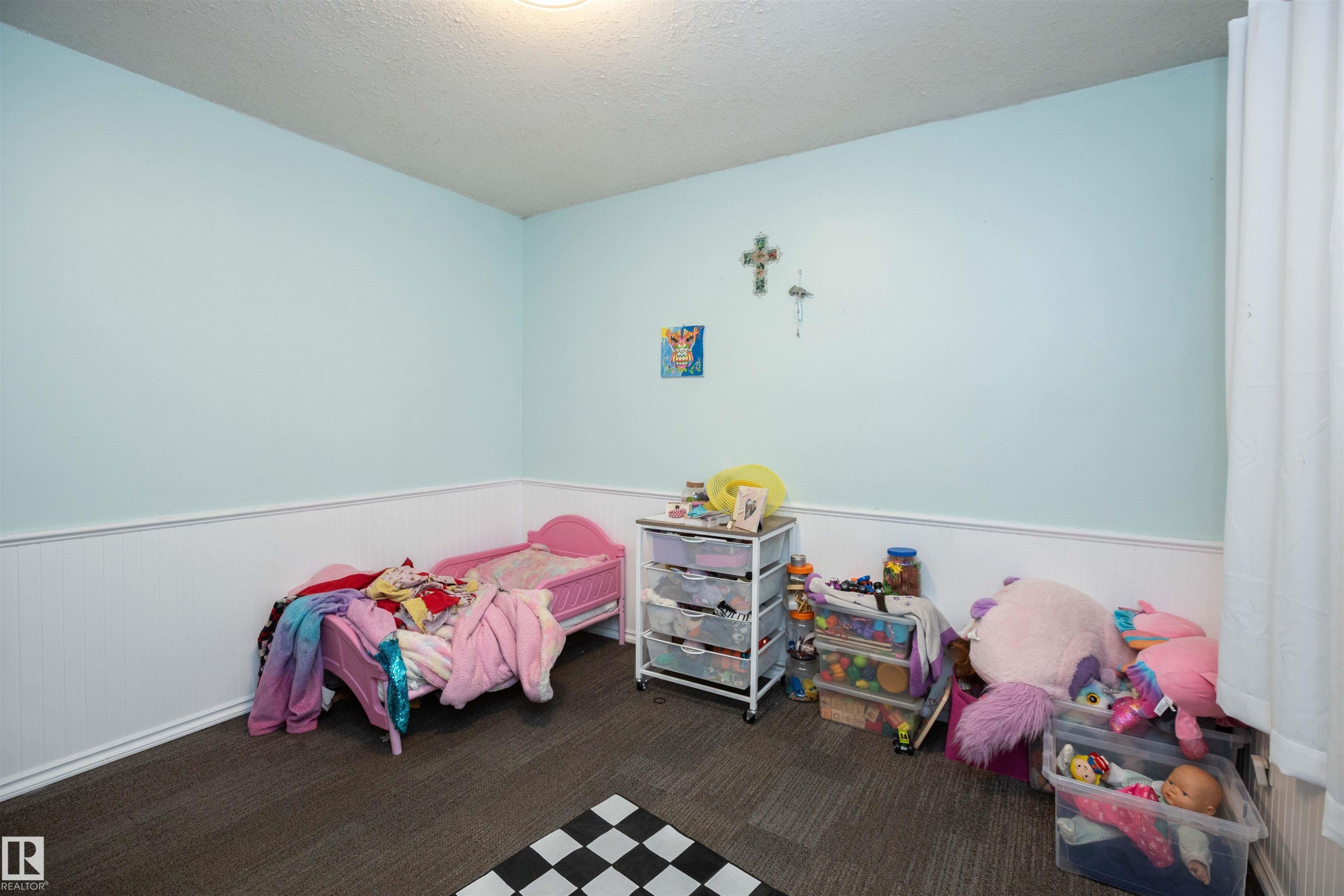 The room features light blue walls with white wainscoting and dark grey carpeted flooring - 4420 56 Avenue, Barrhead, AB - Indoor Photo Showing Bedroom