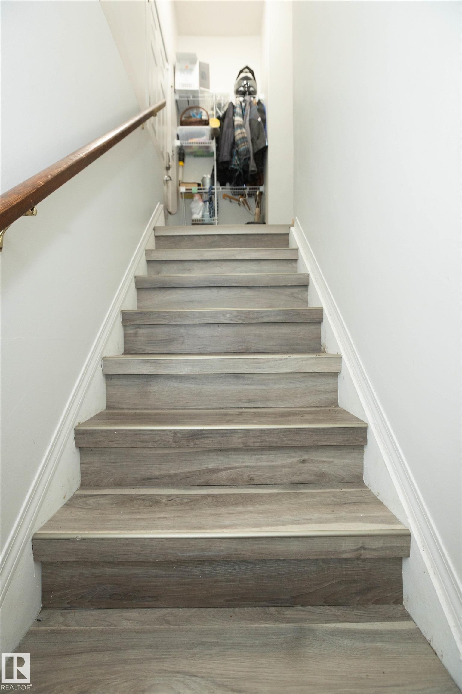 Staircase featuring wood-look treads, white risers, and a wooden handrail - 4420 56 Avenue, Barrhead, AB - Indoor Photo Showing Other Room