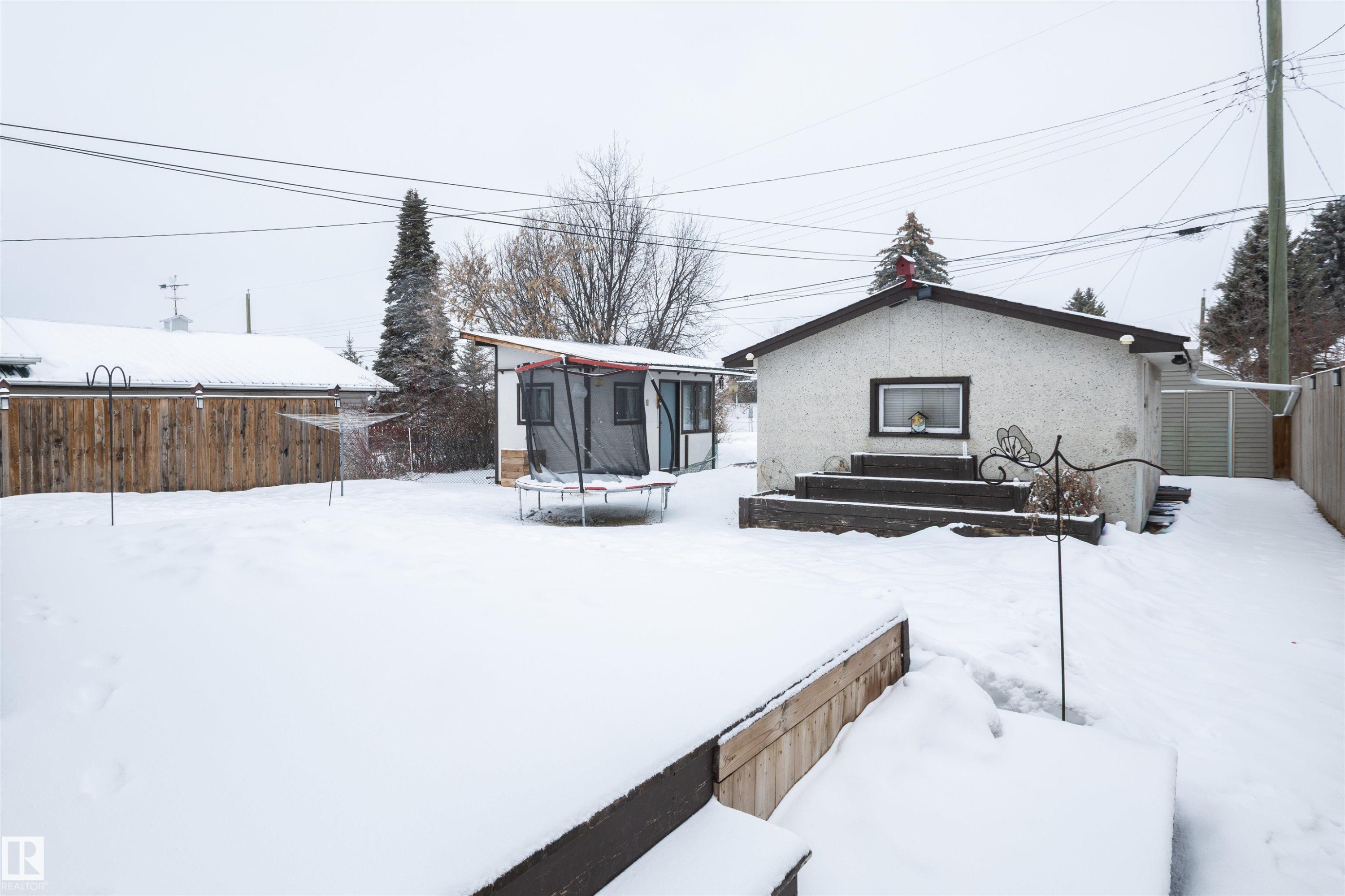 The property features a spacious backyard with a deck and a separate storage shed - 4420 56 Avenue, Barrhead, AB - Outdoor