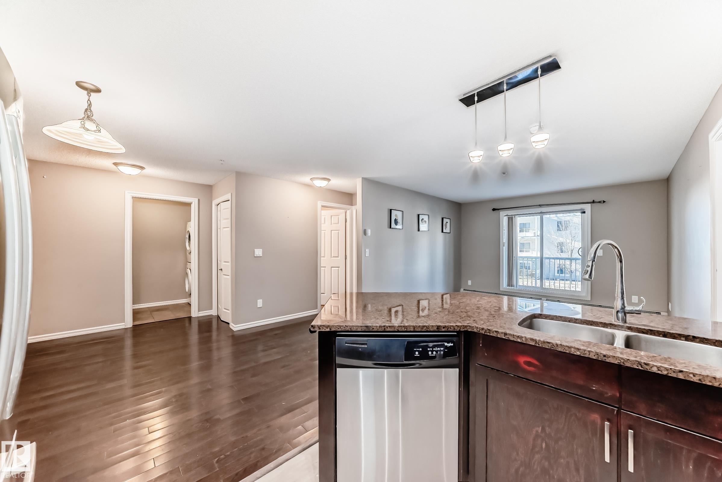 The kitchen features a granite countertop, a double basin sink with a gooseneck faucet, and a stainless steel dishwasher - 208 2204 44 Ave, Edmonton, AB - Indoor Photo Showing Kitchen With Double Sink