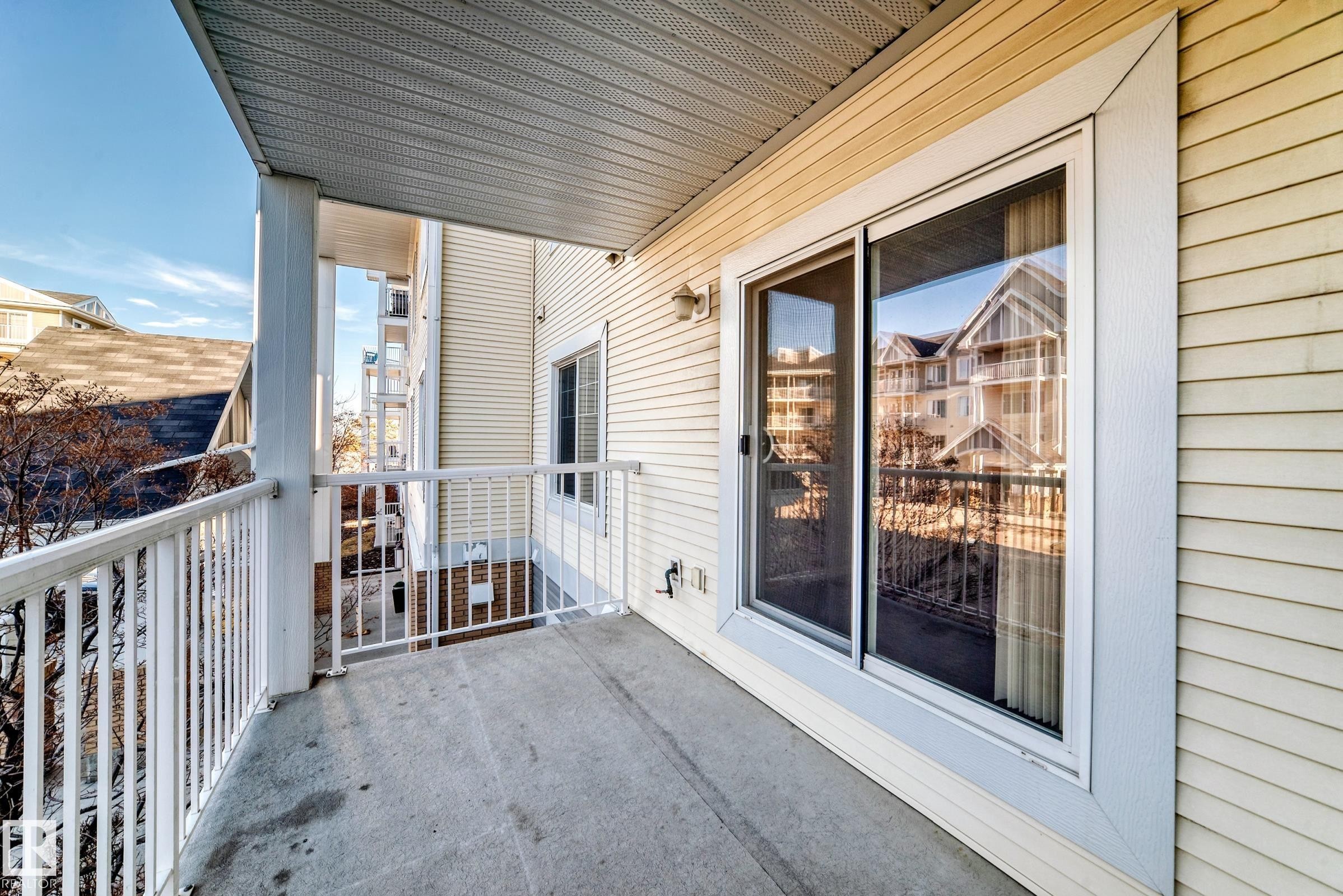 The property features an outdoor balcony with a concrete floor and white railings - 208 2204 44 Ave, Edmonton, AB - Outdoor With Deck Patio Veranda With Exterior