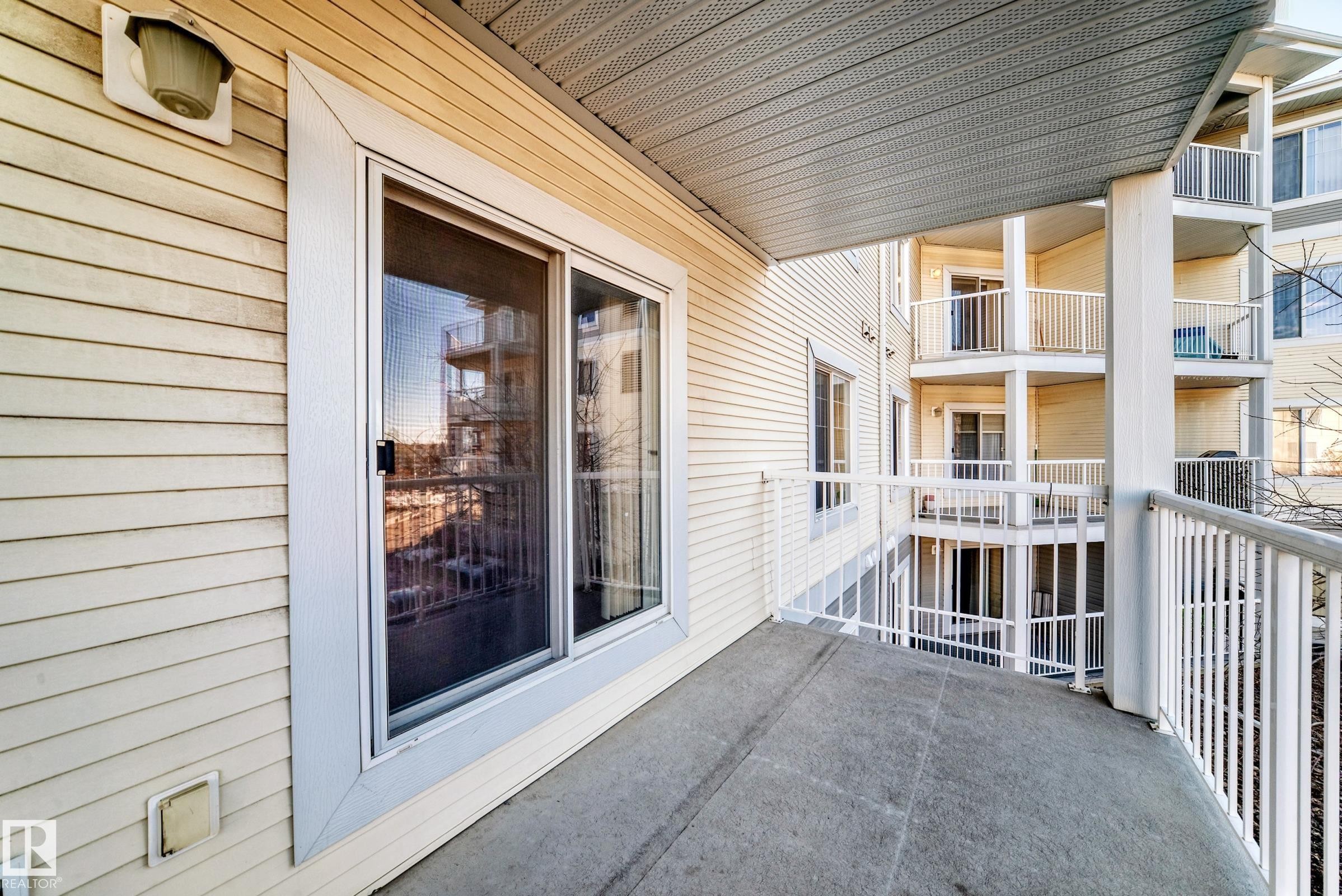 The property features a concrete balcony with white railings and a sliding glass door - 208 2204 44 Ave, Edmonton, AB - Outdoor With Balcony With Exterior