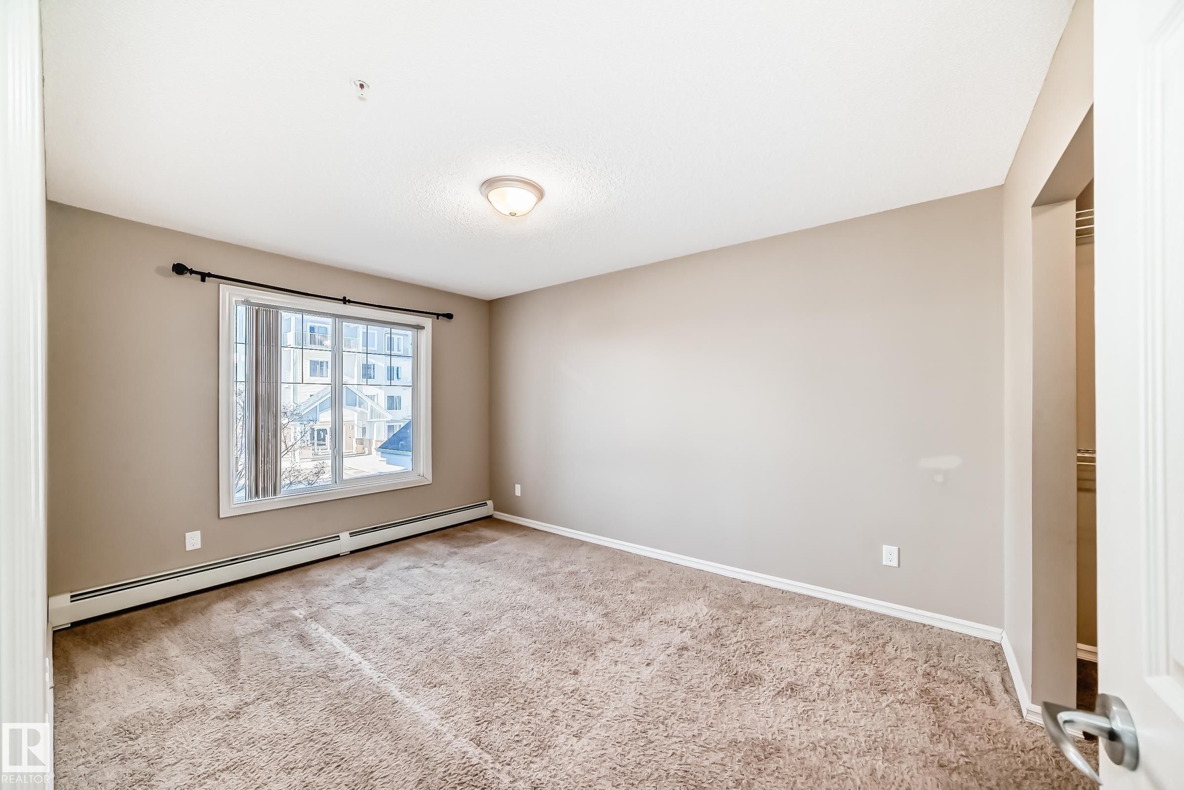 This room features neutral-toned walls, a large window, and carpeted flooring - 208 2204 44 Ave, Edmonton, AB - Indoor Photo Showing Other Room