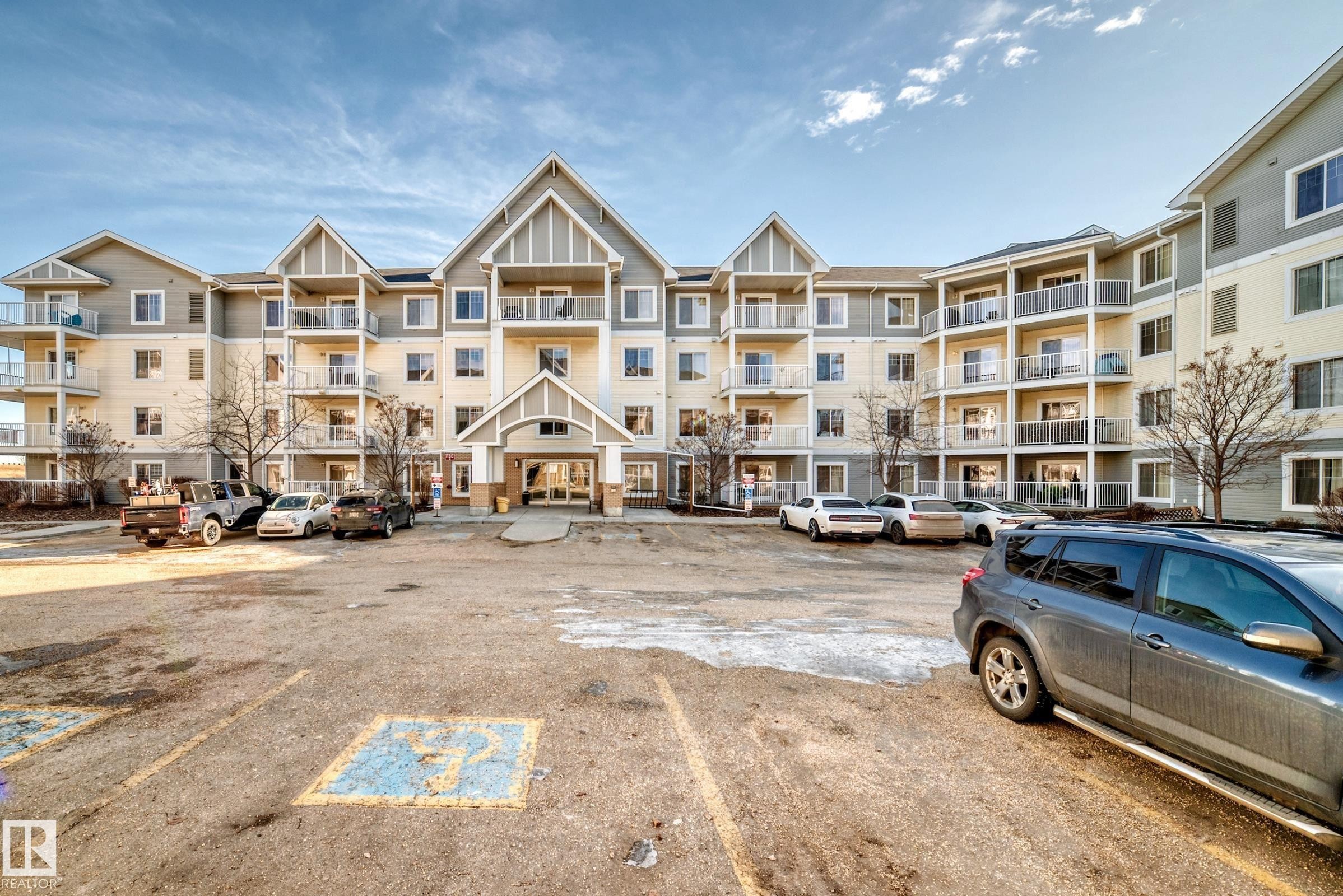 The property features a large exterior with balconies on each level, a covered main entrance, and a spacious parking area - 208 2204 44 Ave, Edmonton, AB - Outdoor With Balcony With Facade