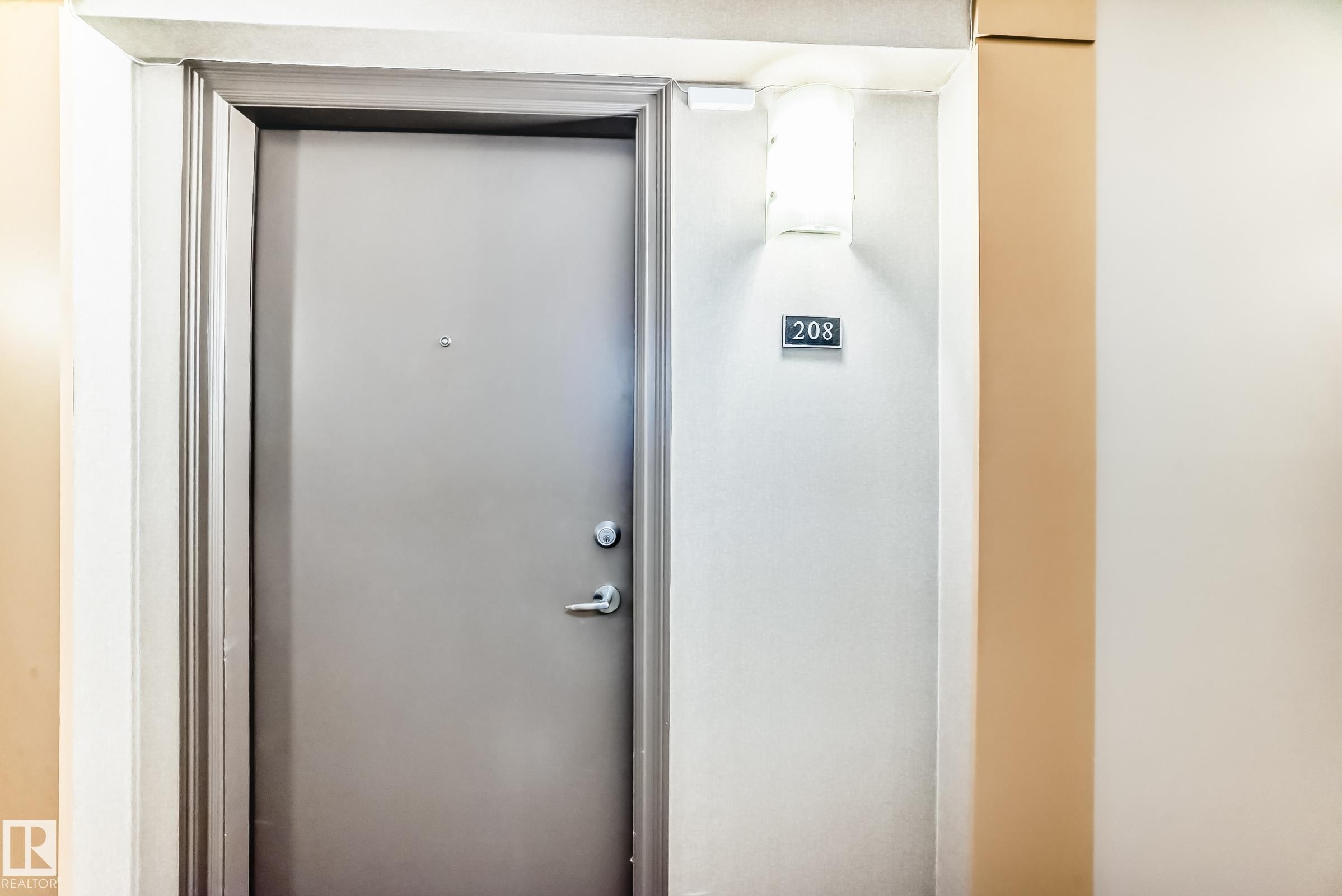 The property features a private entrance with a gray door and a modern wall-mounted light fixture - 208 2204 44 Ave, Edmonton, AB - Indoor