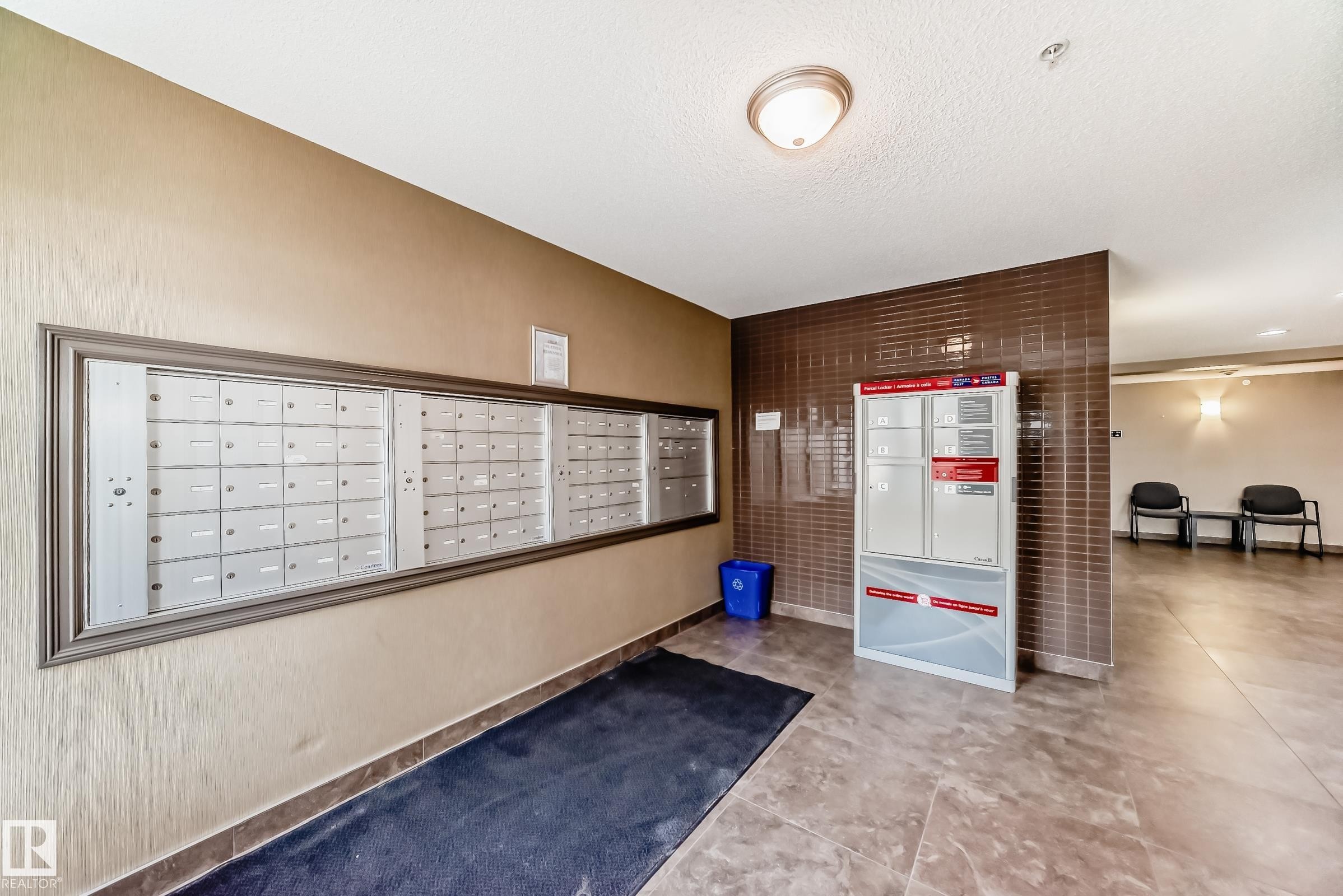 The property features a dedicated mailroom with individual mailboxes and package lockers, set against a backdrop of neutral-toned walls and patterned floor tiles - 208 2204 44 Ave, Edmonton, AB - Indoor Photo Showing Other Room