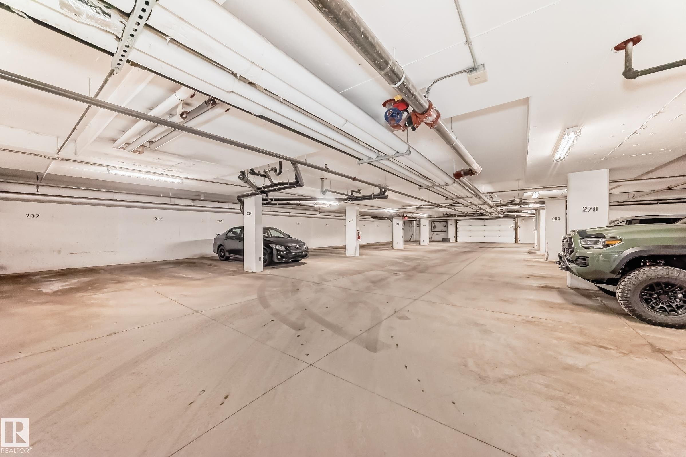 Designated parking space with a concrete floor, bright overhead lighting, and numbered identification - 208 2204 44 Ave, Edmonton, AB - Indoor Photo Showing Garage