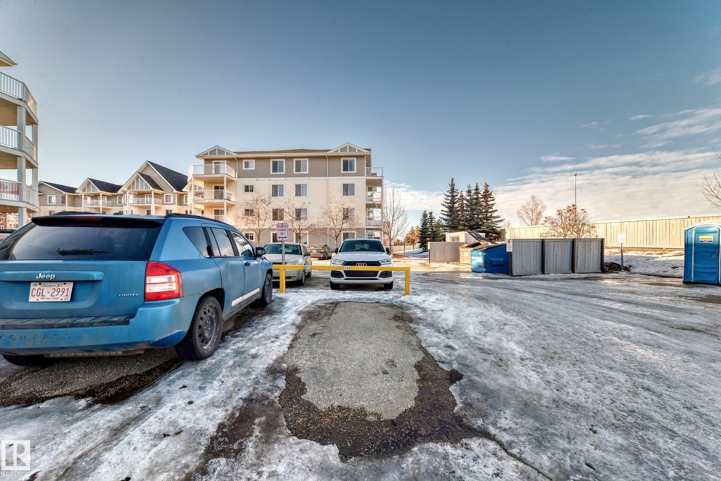 Exterior view of the property's grounds, featuring a parking area and a multi-story building with balconies - 208 2204 44 Ave, Edmonton, AB - Outdoor
