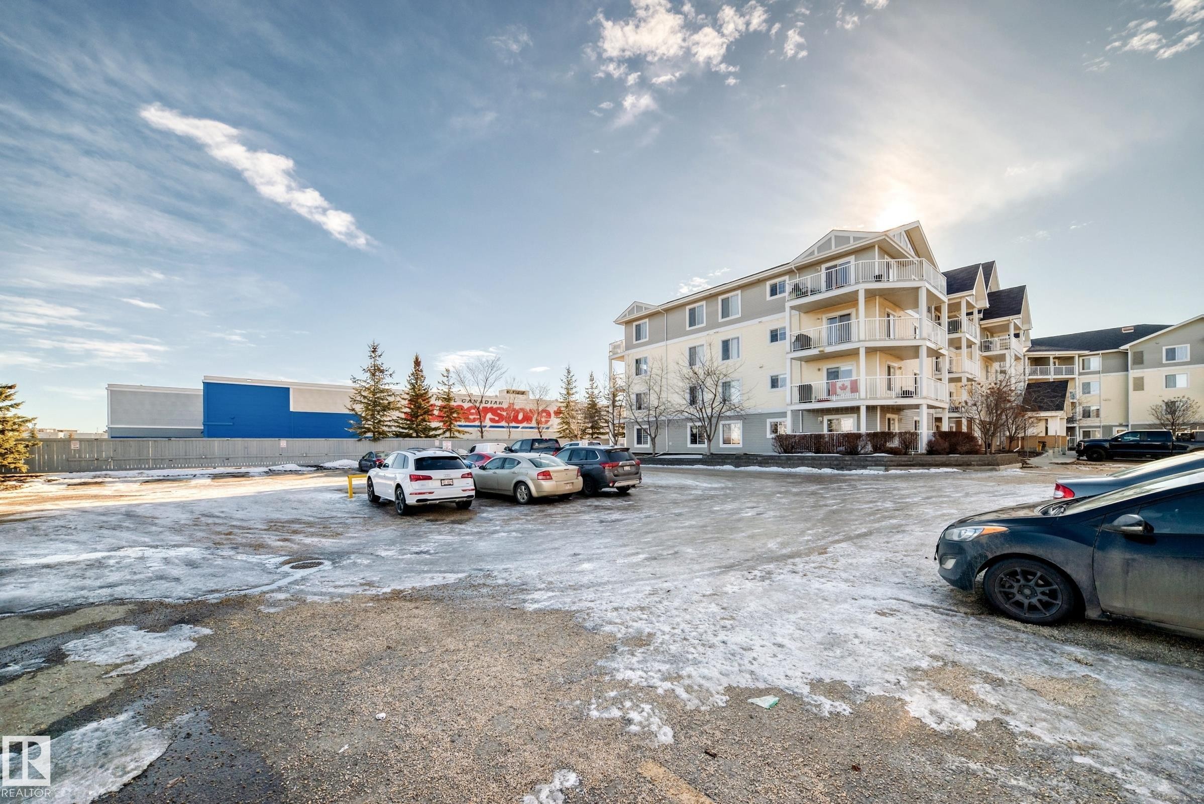 The property features a multi-story building with balconies, set within a paved parking area - 208 2204 44 Ave, Edmonton, AB - Outdoor
